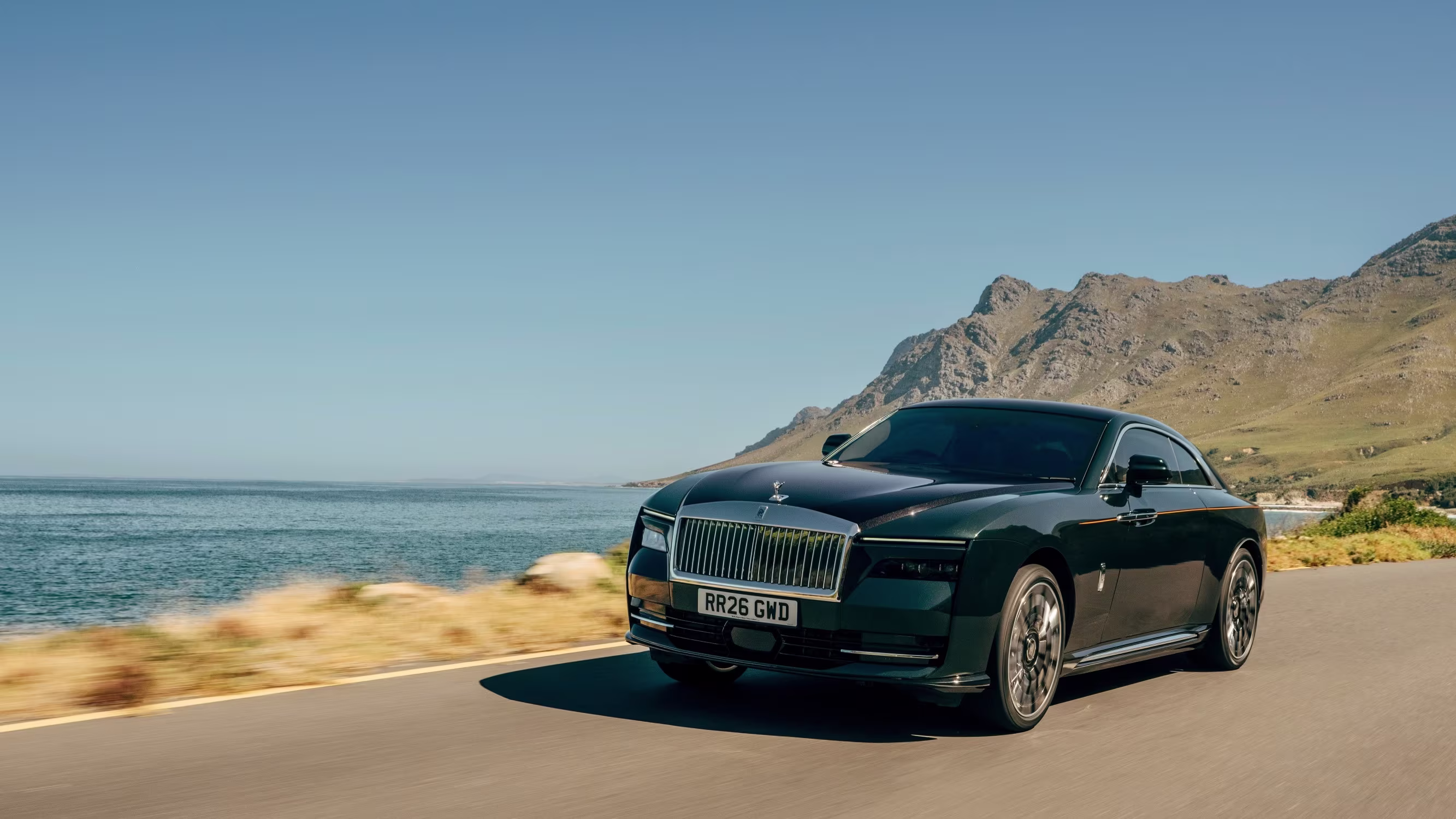 Rolls-Royce Spectre Series II na cor prata em movimento por uma estrada de asfalto.