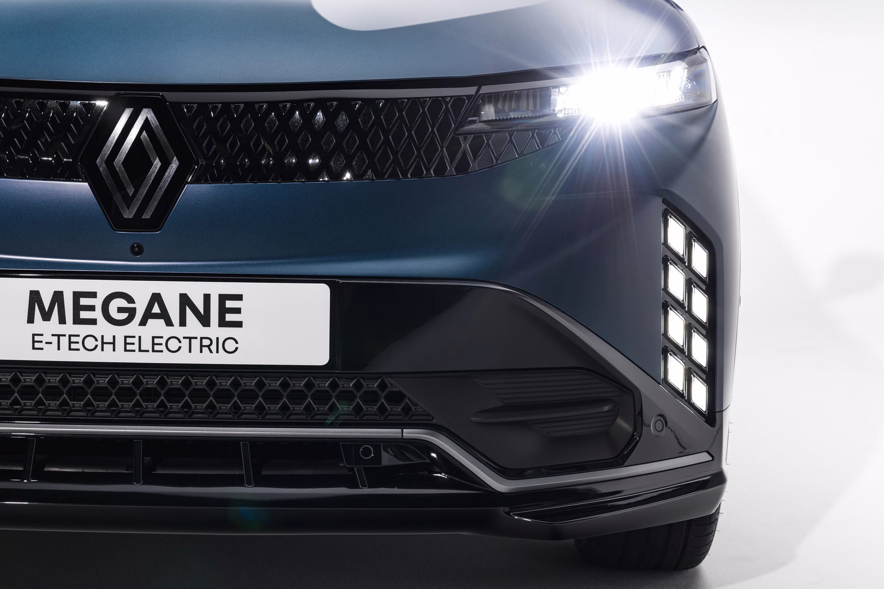 Frente do Renault Megane E-Tech Electric com farol aceso em estúdio