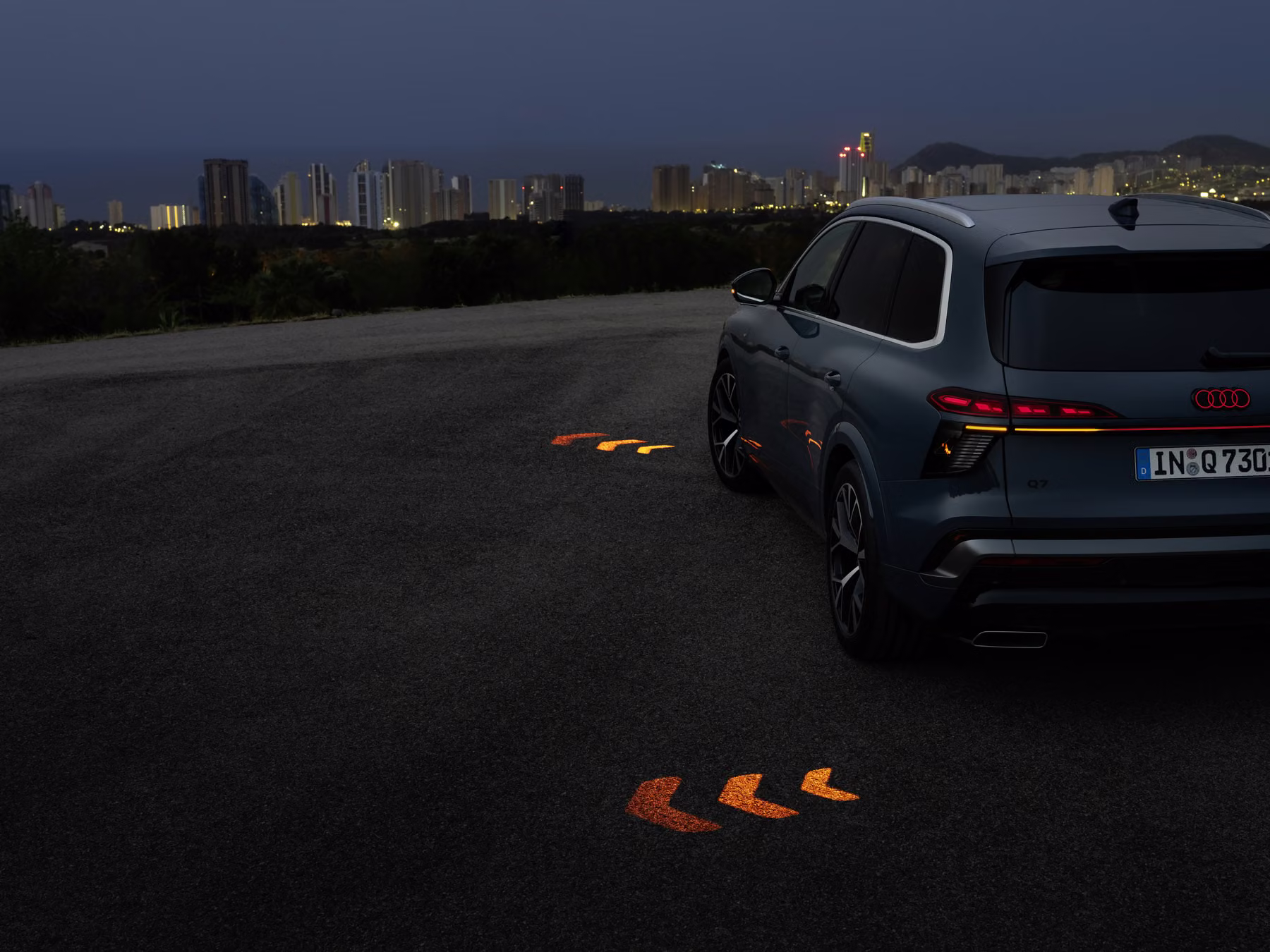 Audi Q7 em ambiente escuro com setas avançadas projetadas no solo