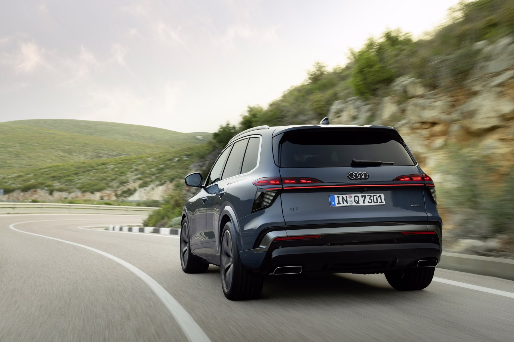 Audi Q7 em movimento visto de trás em estrada sinuosa
