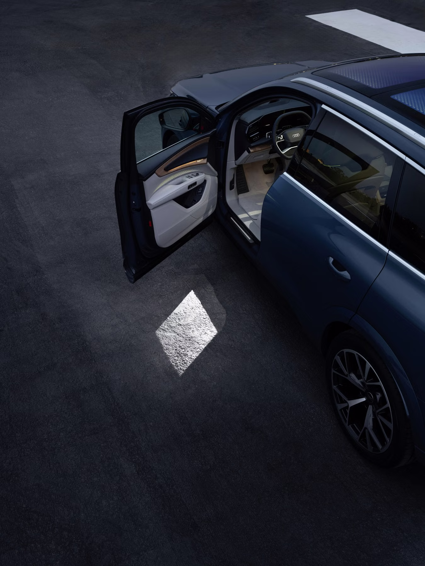 Porta dianteira do Audi Q7 aberta com projeção luminosa em formato de losango no solo