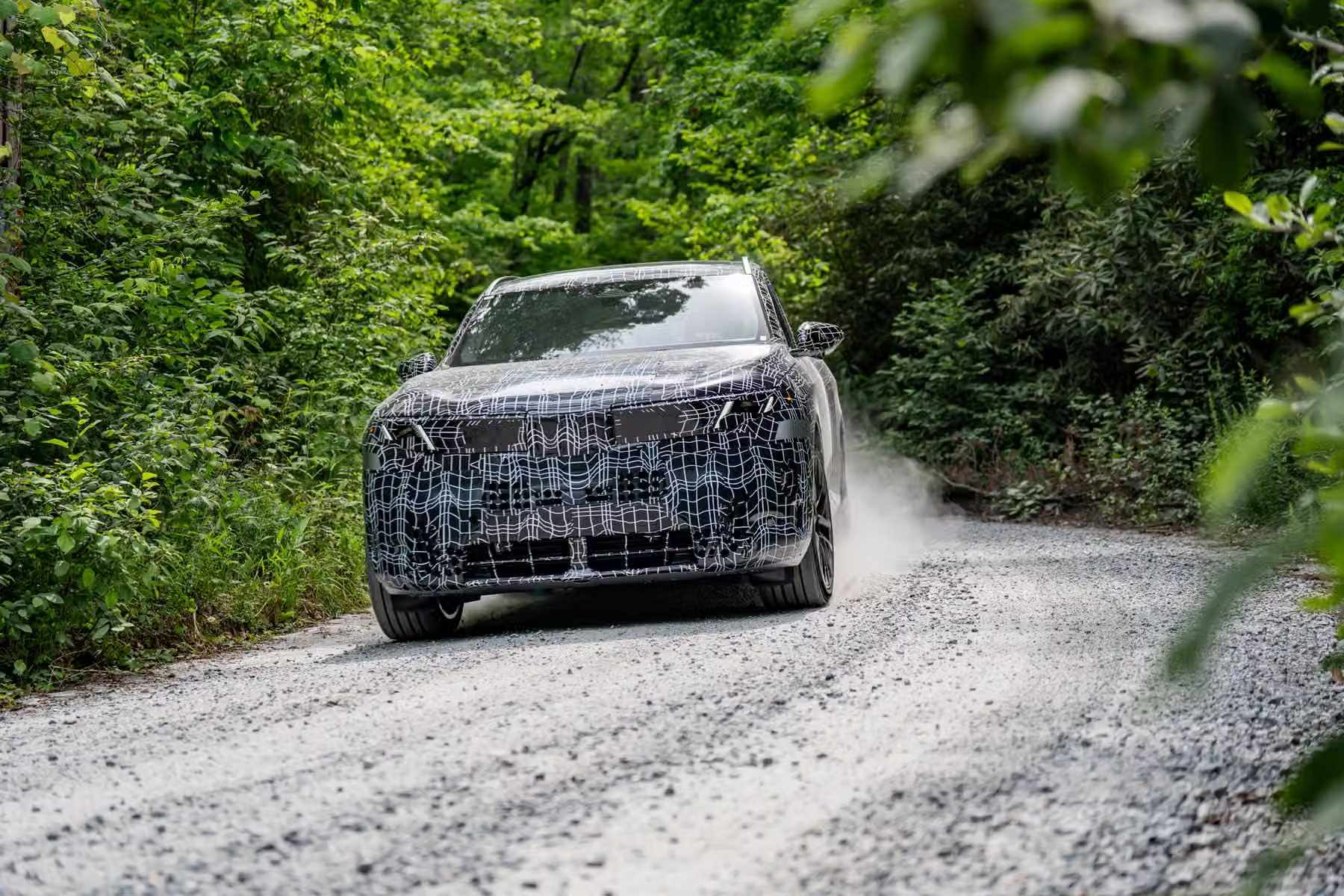 Novo BMW X5 camuflado em estrada de terra e vegetação densa