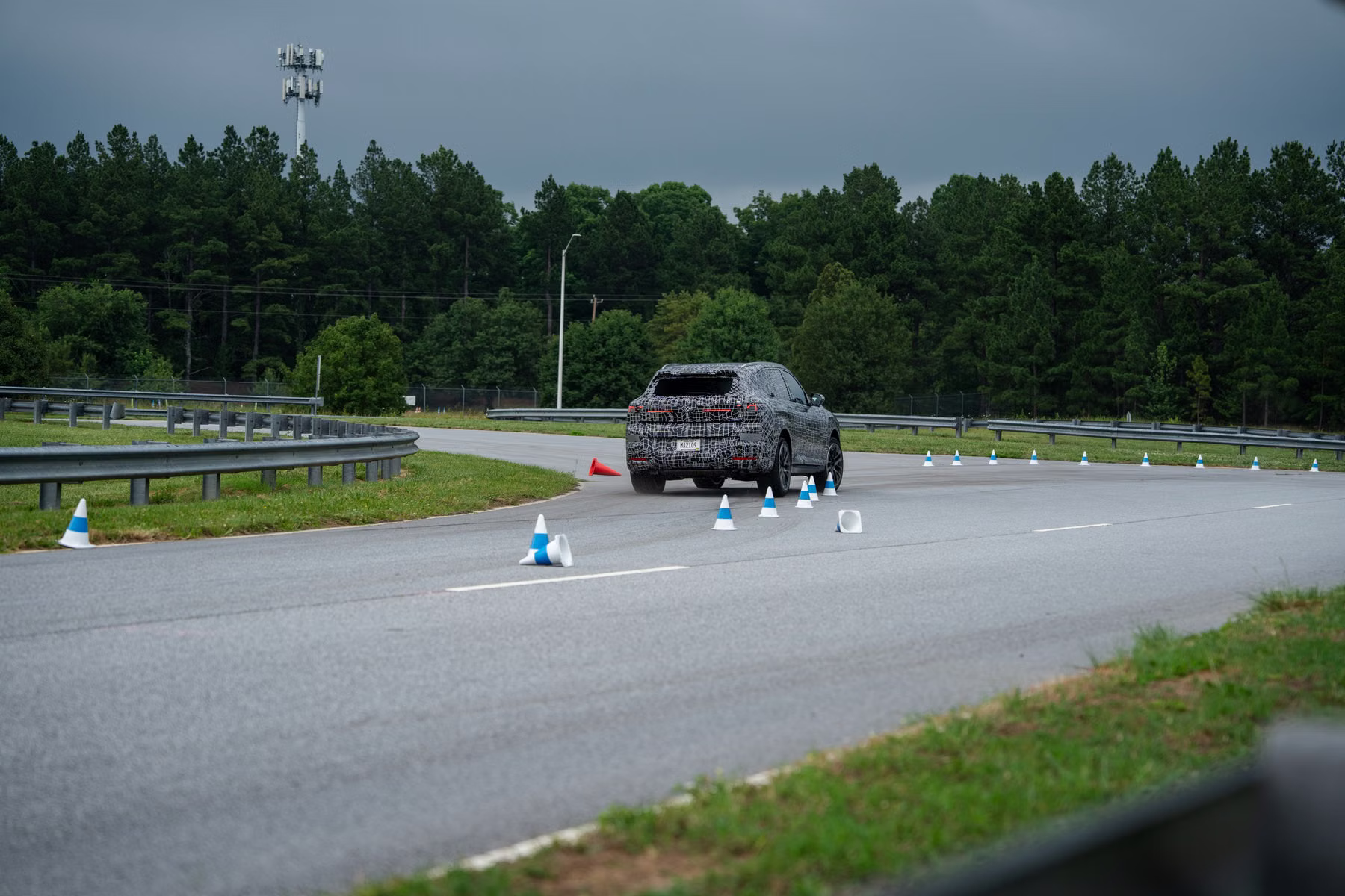 Protótipo do novo BMW X5 em pista de testes visto de longe entre cones