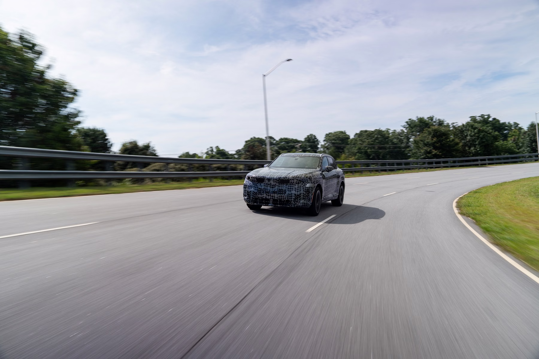 Novo BMW X5 camuflado em curva de rodovia durante teste dinâmico