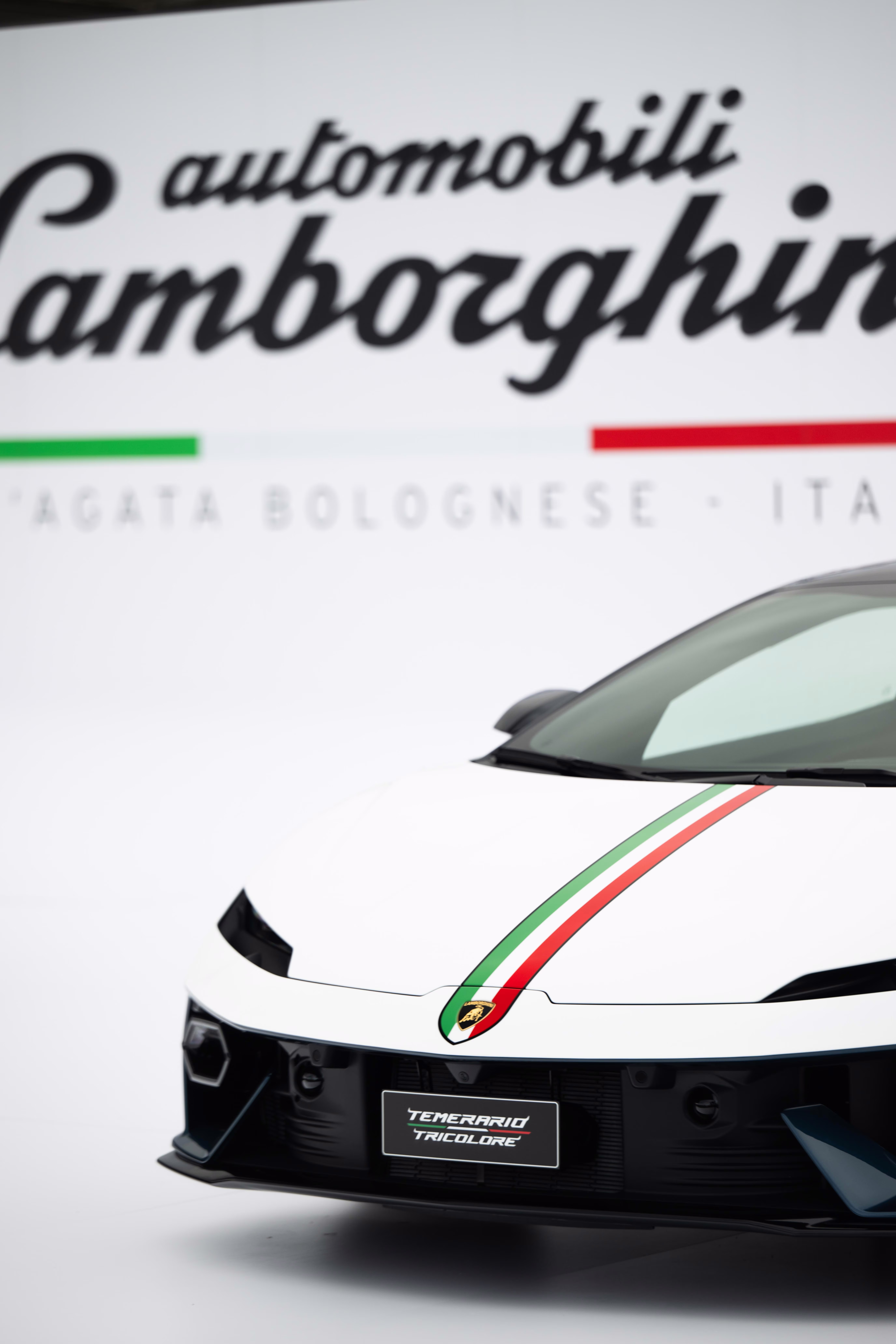 Recorte vertical da frente do Lamborghini Temerario Tricolore diante do logotipo da marca