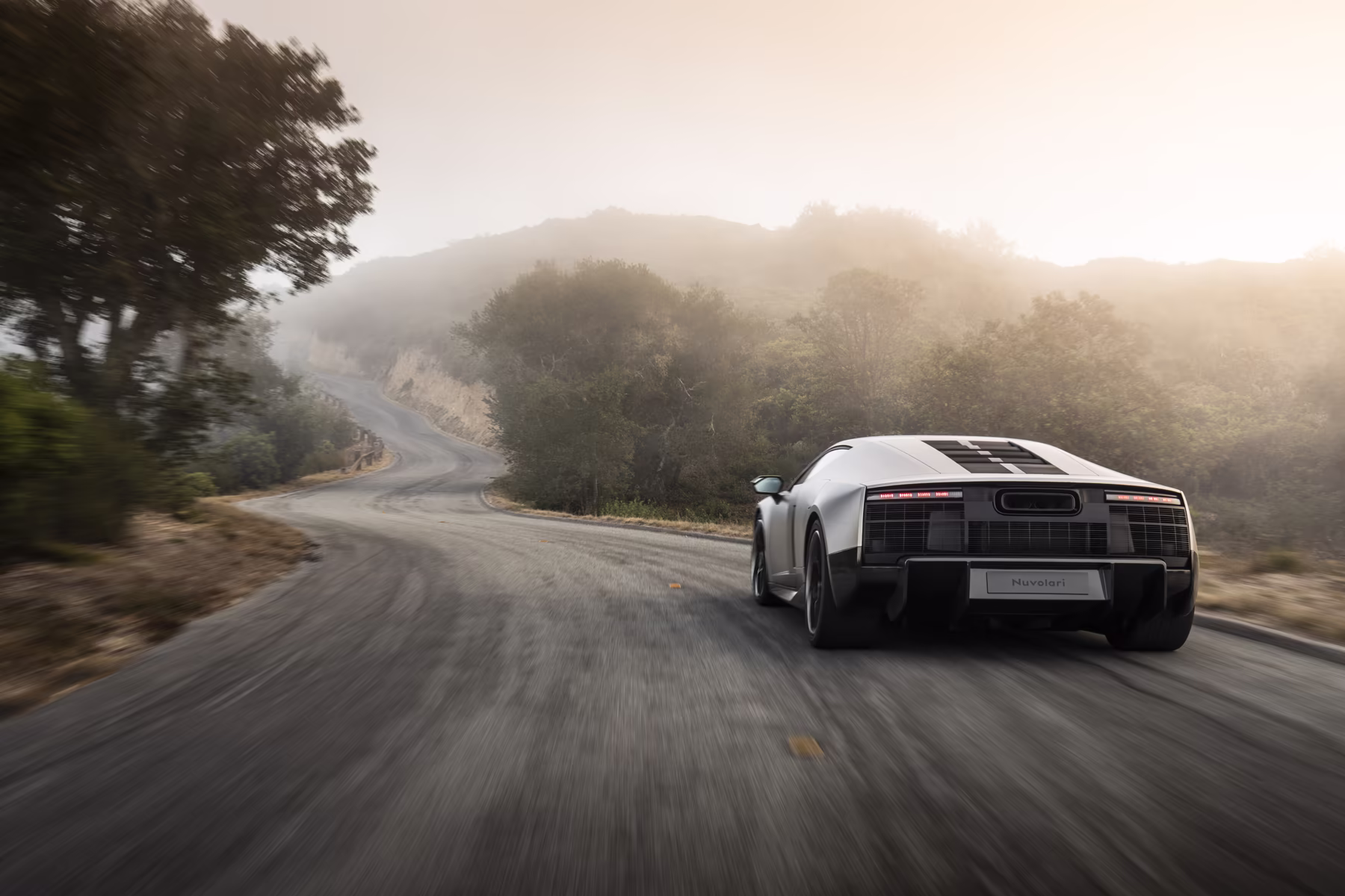 Audi Nuvolari em movimento por estrada sinuosa entre colinas