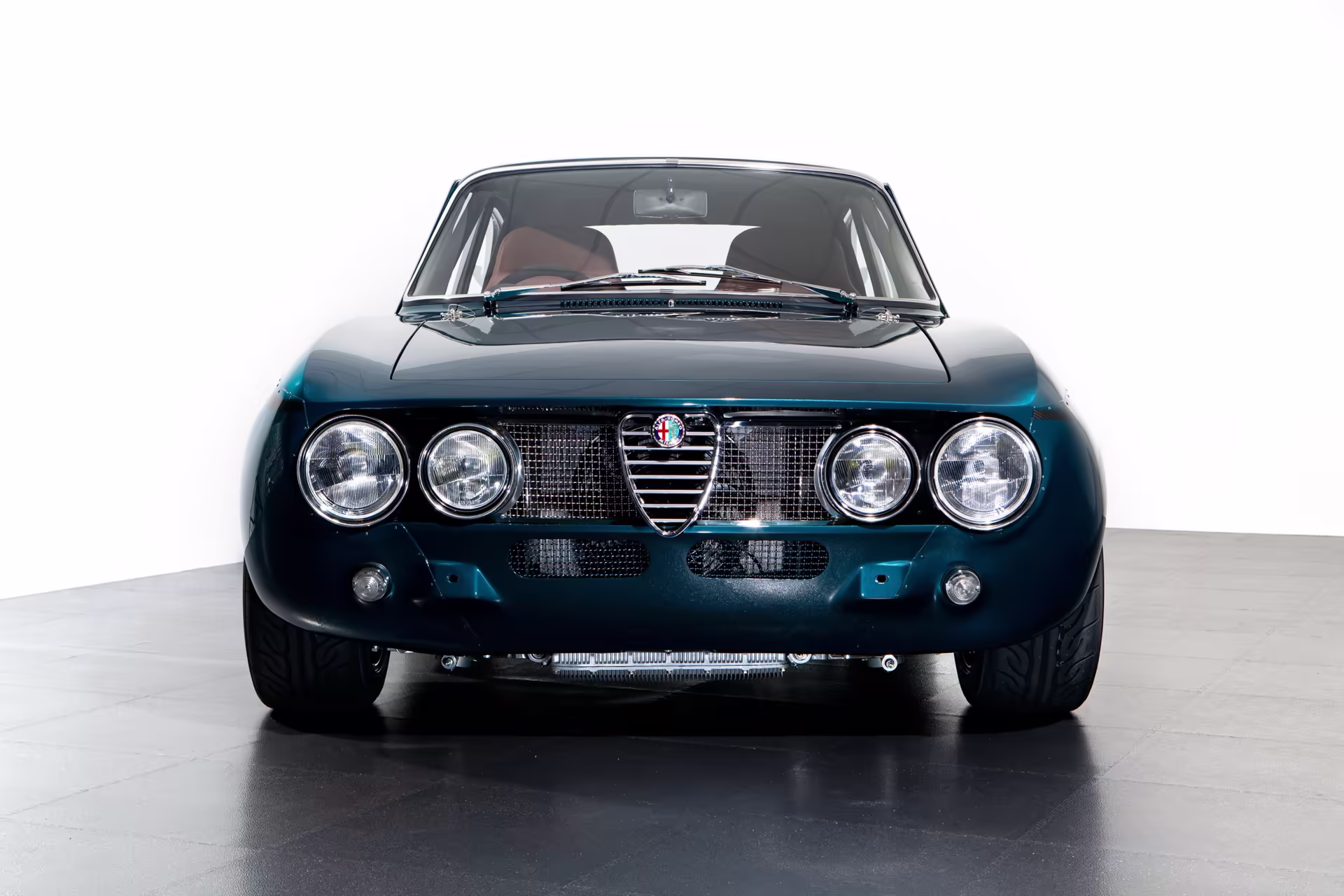 Detalhe frontal do GTA-R 024 azul com faróis auxiliares e grelha Alfa Romeo