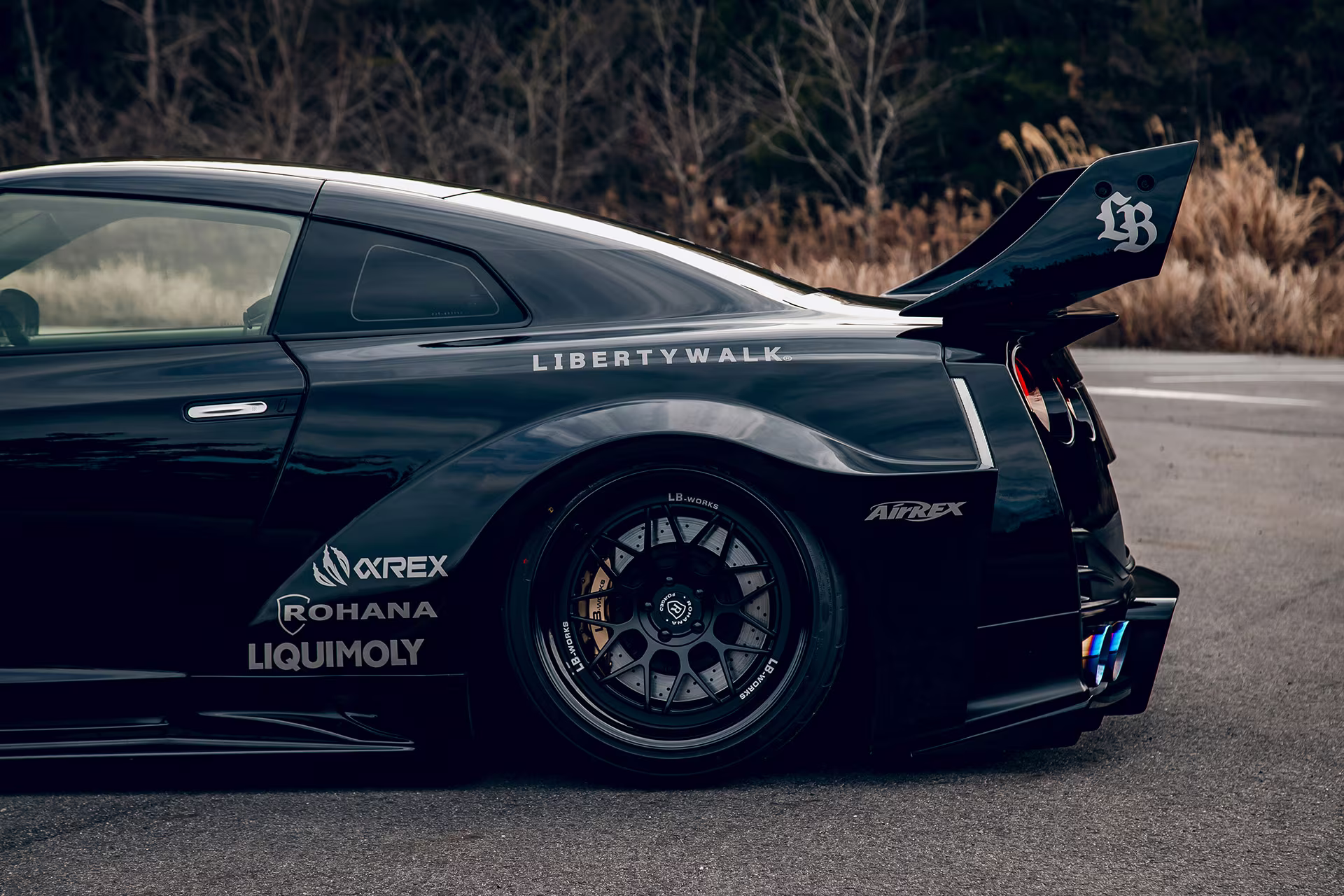 Detalhe da traseira alargada do LB-Silhouette WORKS GT preto com stickers Liberty Walk, Airex, Rohana e Liqui Moly