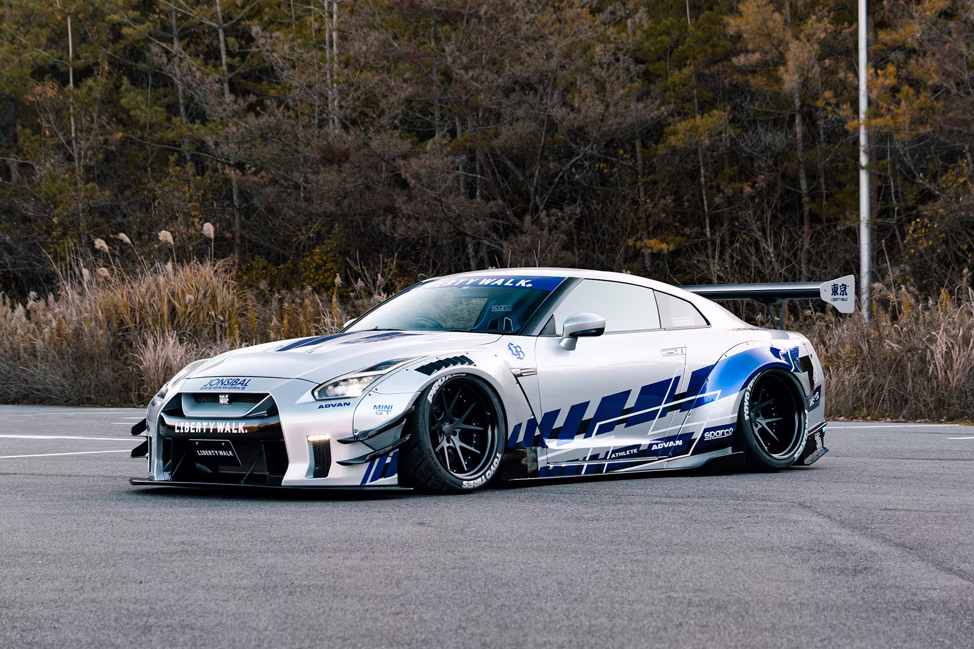 LB-WORKS Nissan GT-R R35 Type 2 branco com grafismo azul em três-quartos frontal em campo