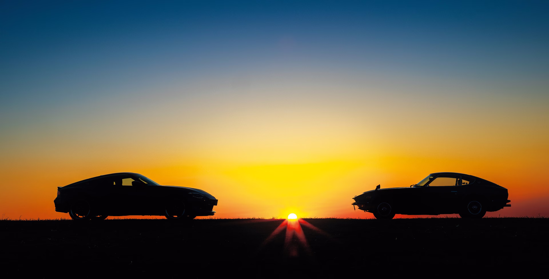 Silhuetas de duas gerações do Nissan Z ao pôr do sol