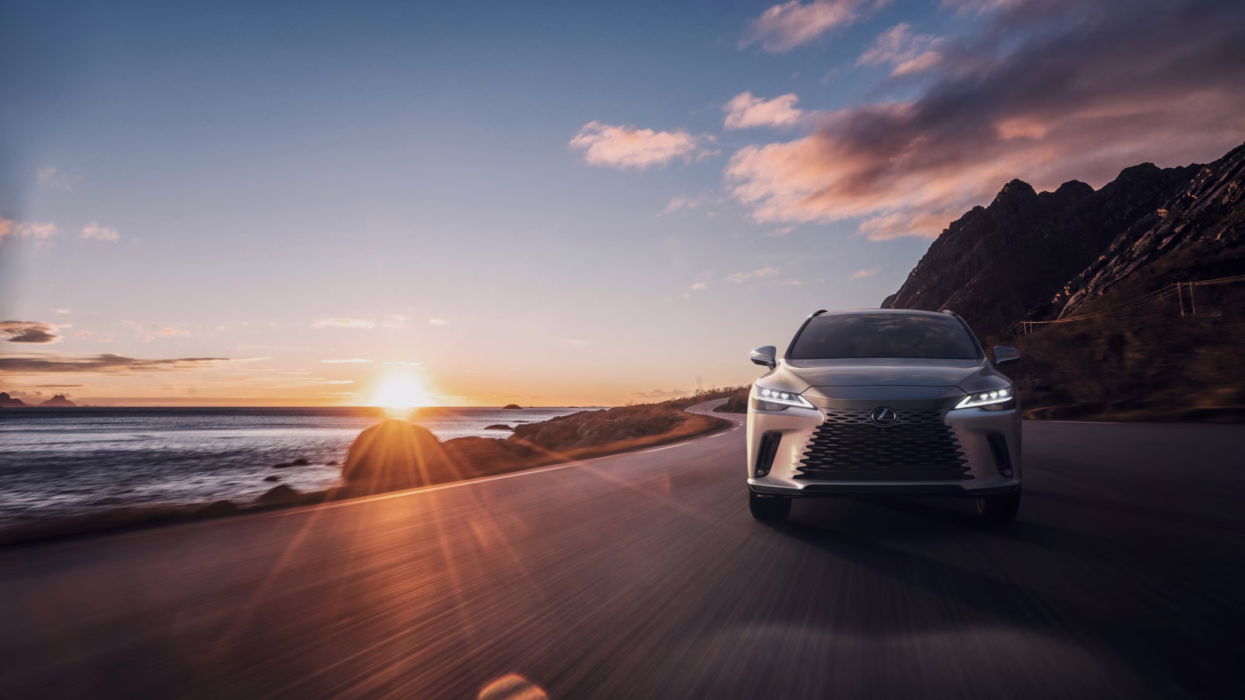 RX 350 em uma estrada litorânea ao pôr do sol, visto de frente. Foto de divulgação da Lexus.