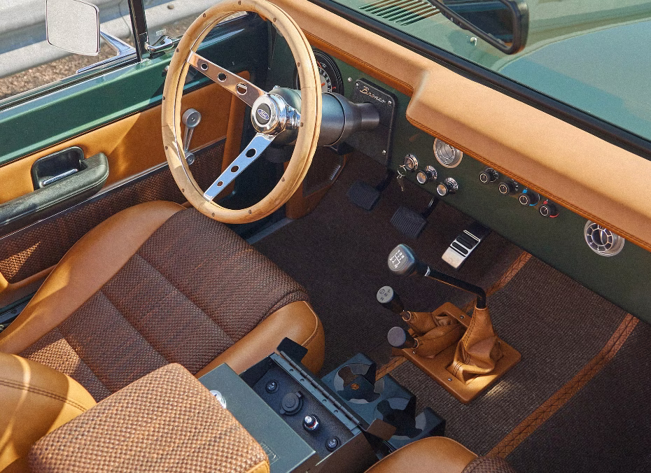 Cabine de outro Bronco da CFB com volante de madeira, bancos caramelo e carroceria verde