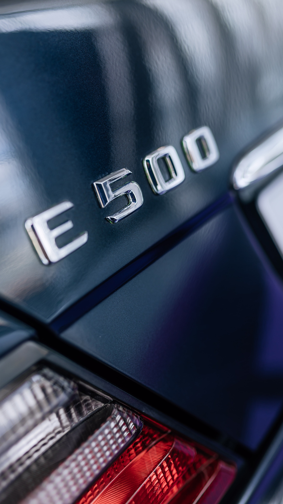 Foto vertical de divulgação do emblema e da lanterna traseira do E 500 Limited de 1995