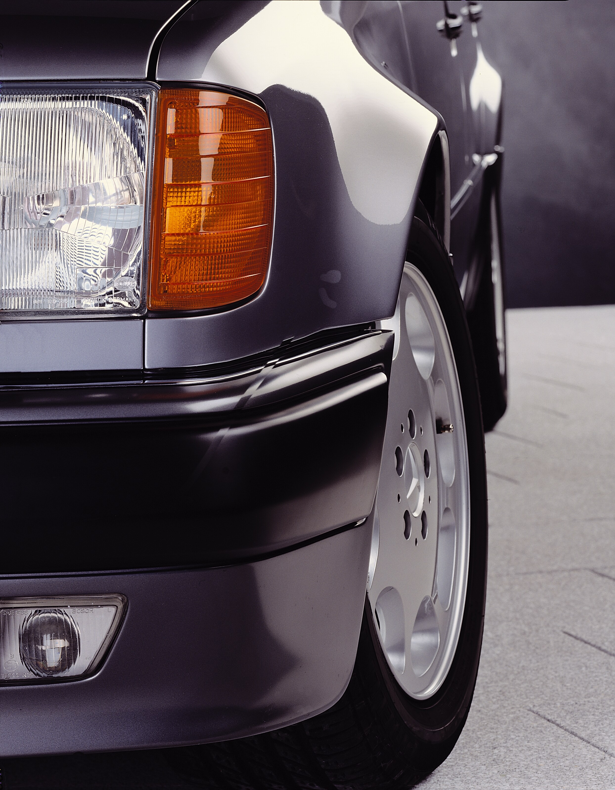 Foto vertical de divulgação de 1990 do para-lama alargado e da roda dianteira do Mercedes-Benz 500 E