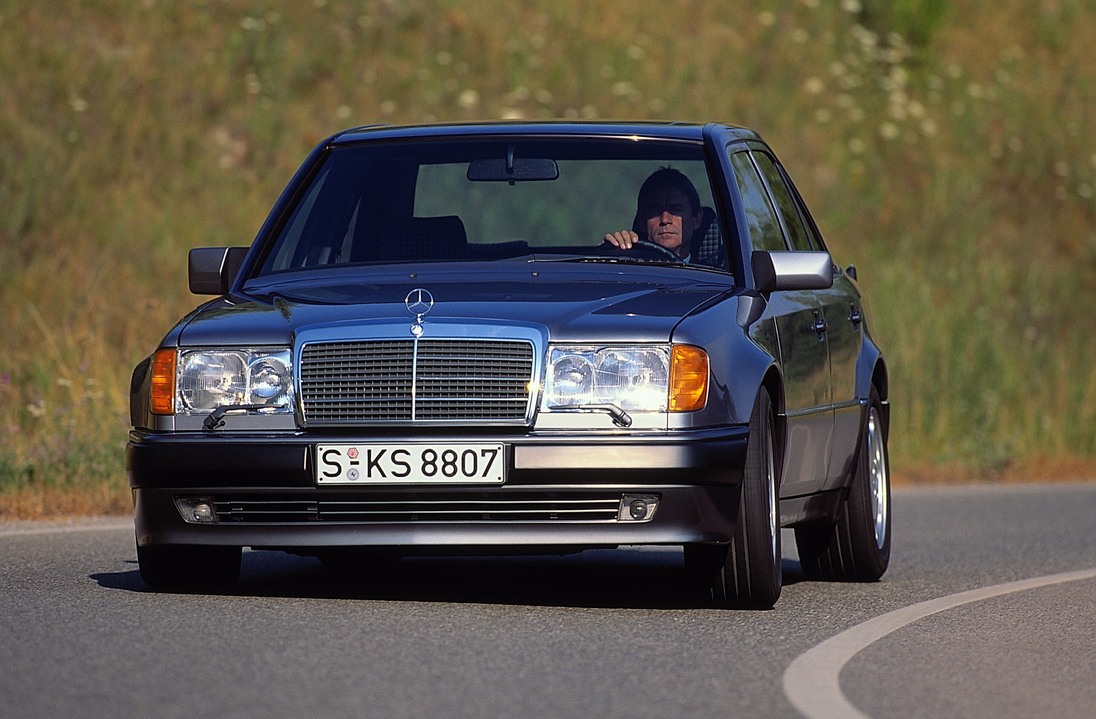 Foto de divulgação de 1990 do Mercedes-Benz 500 E visto de frente em uma estrada