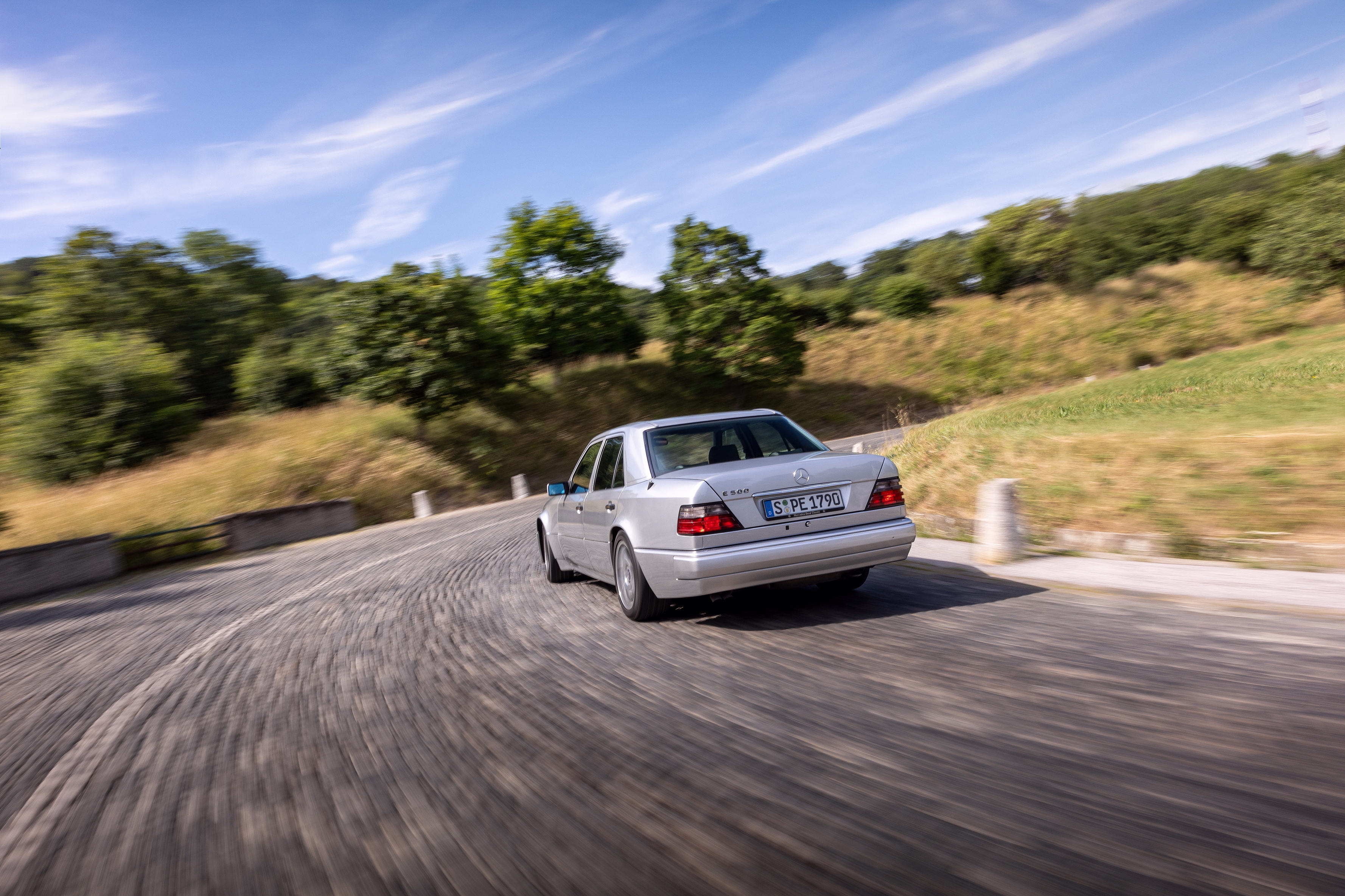 Foto de divulgação do E 500 Limited prata de 1994 visto de trás em uma estrada, fotografado em 2023