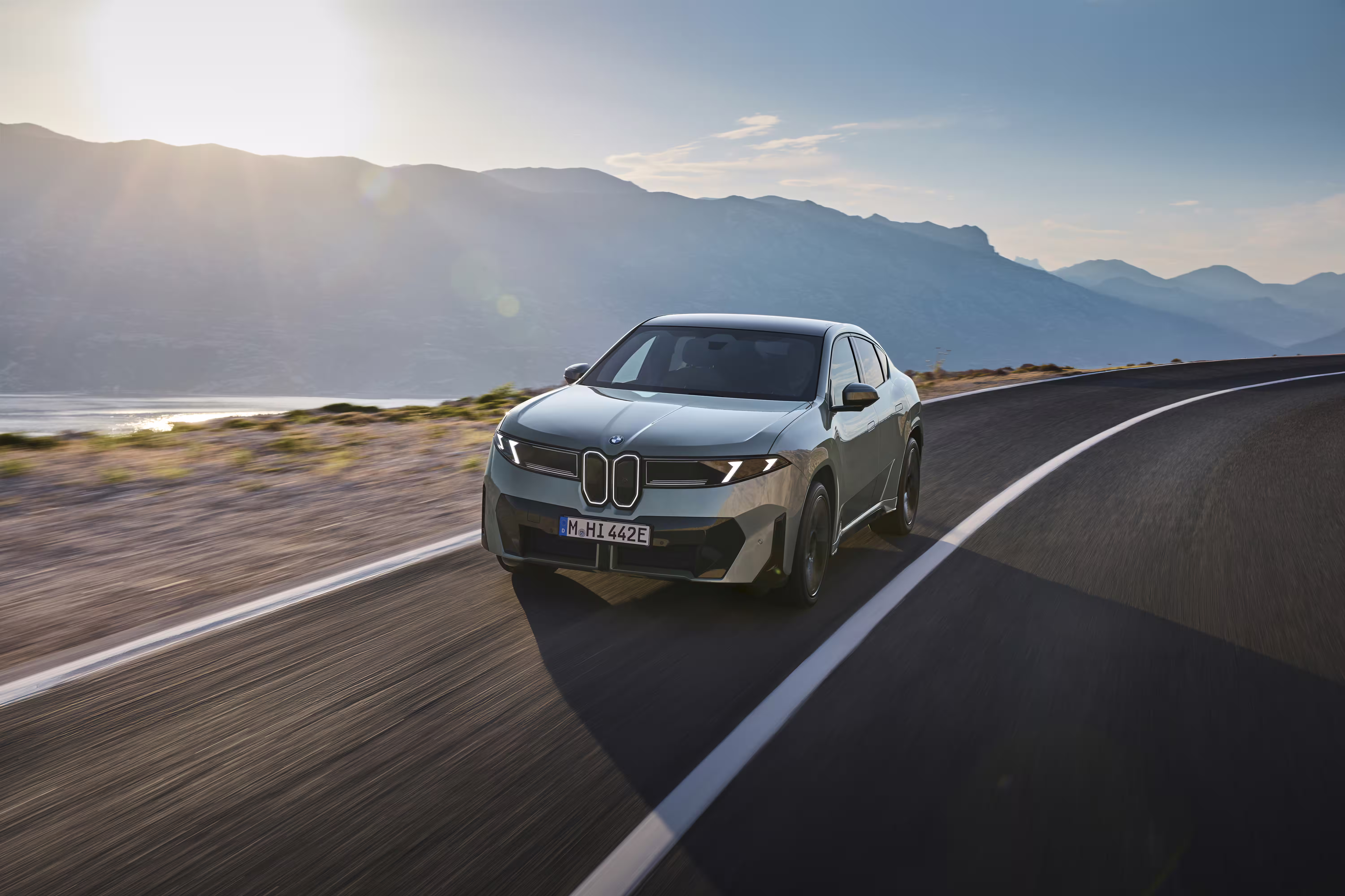 Foto de divulgação da BMW: 50 xDrive visto de frente na estrada, em um ângulo mais elevado sobre o capô.
