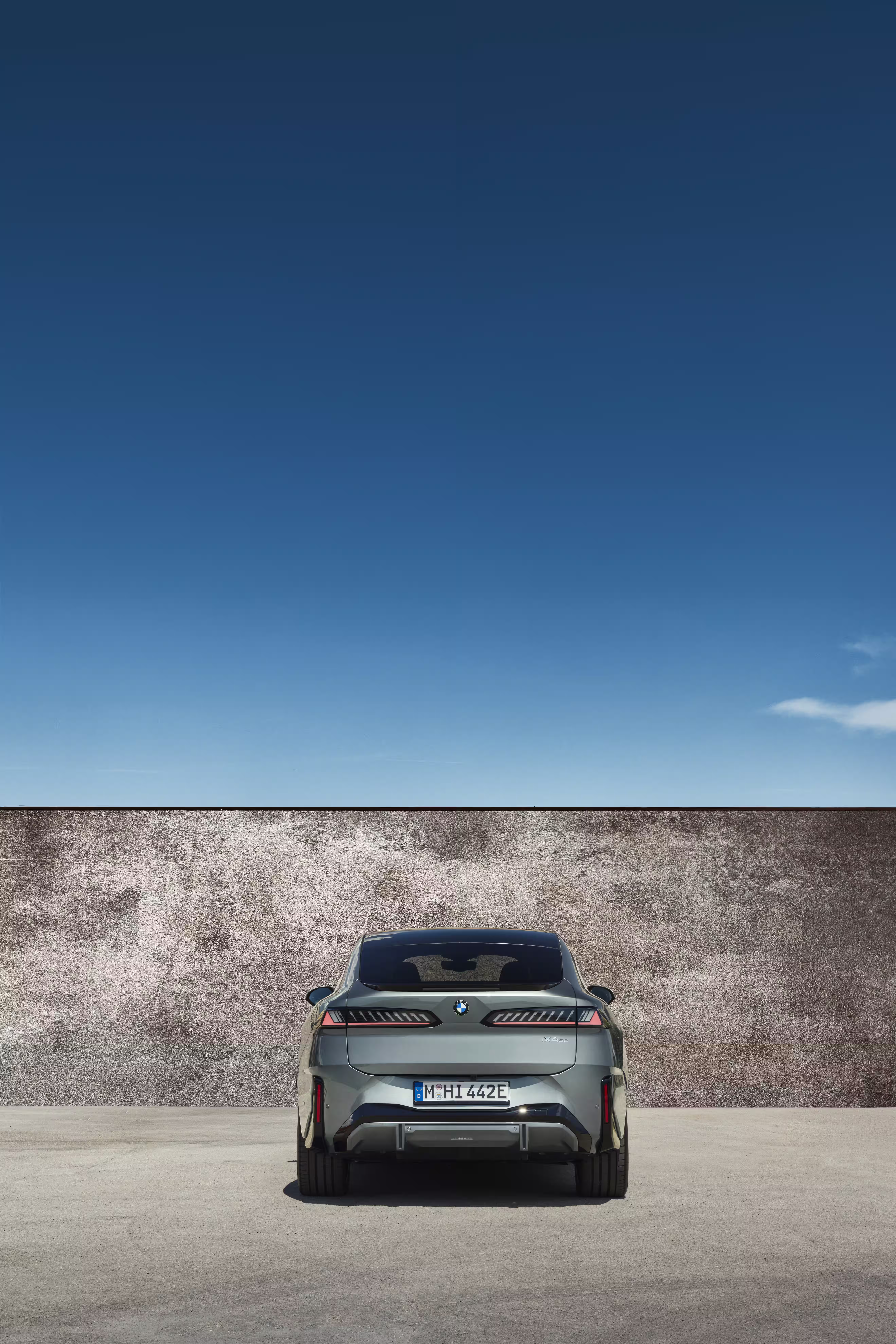 Foto de divulgação da BMW: Foto vertical da traseira do 50 xDrive: lanternas e spoiler preservados no enquadramento.