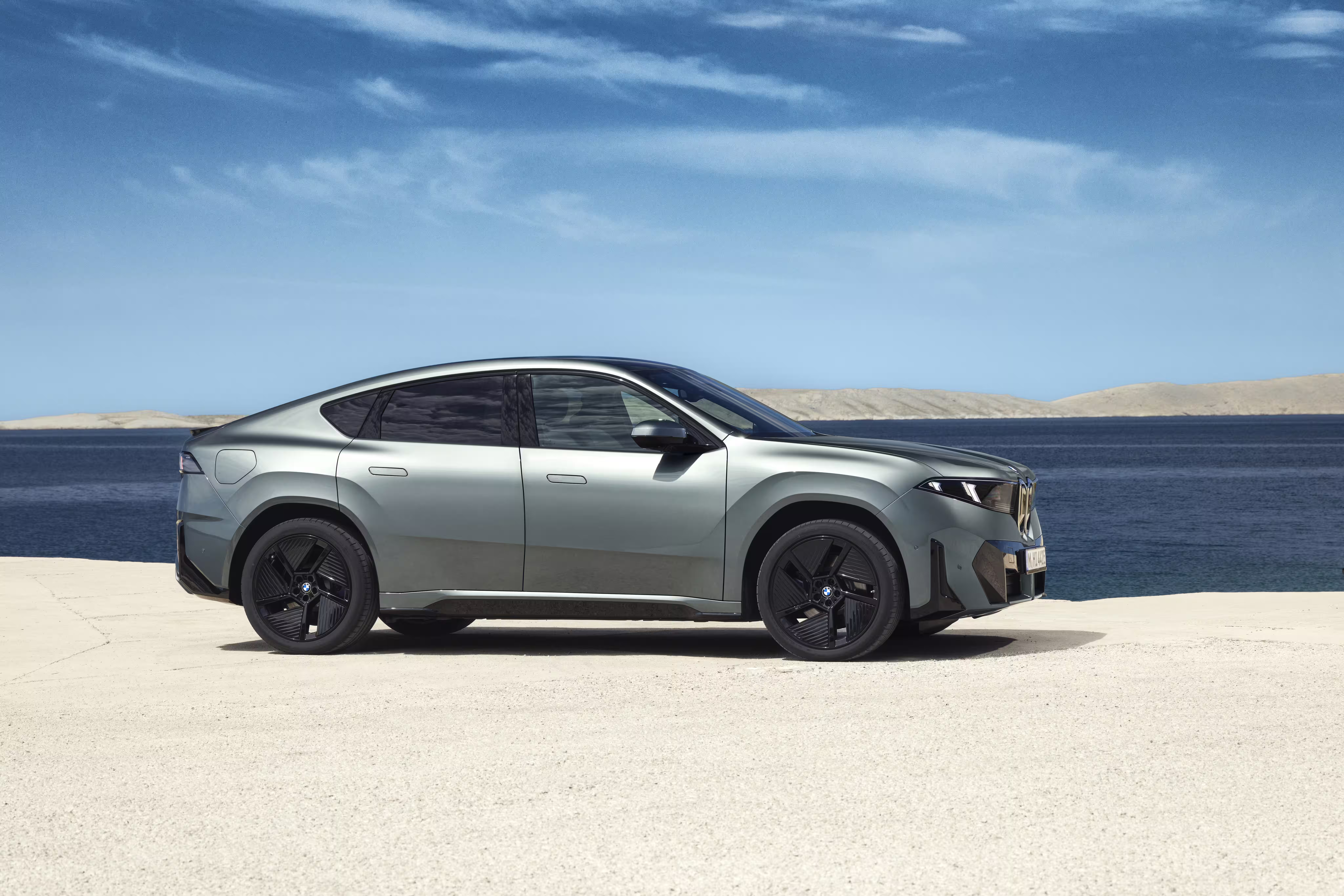 Foto de divulgação da BMW: Frente em três quartos do 50 xDrive no cenário à beira do lago.