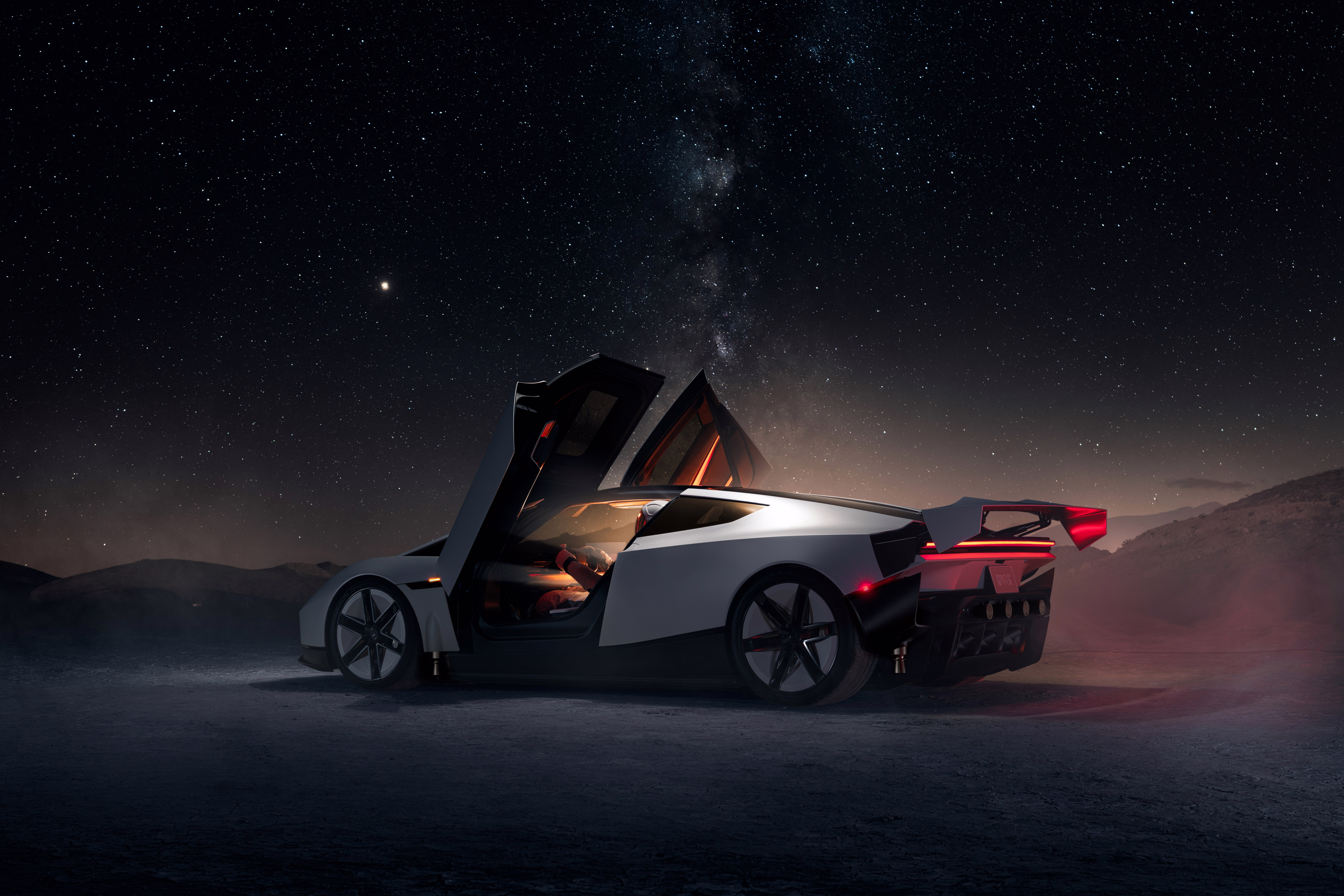 Roadster em três quartos com portas abertas e asa elevada sob céu estrelado
