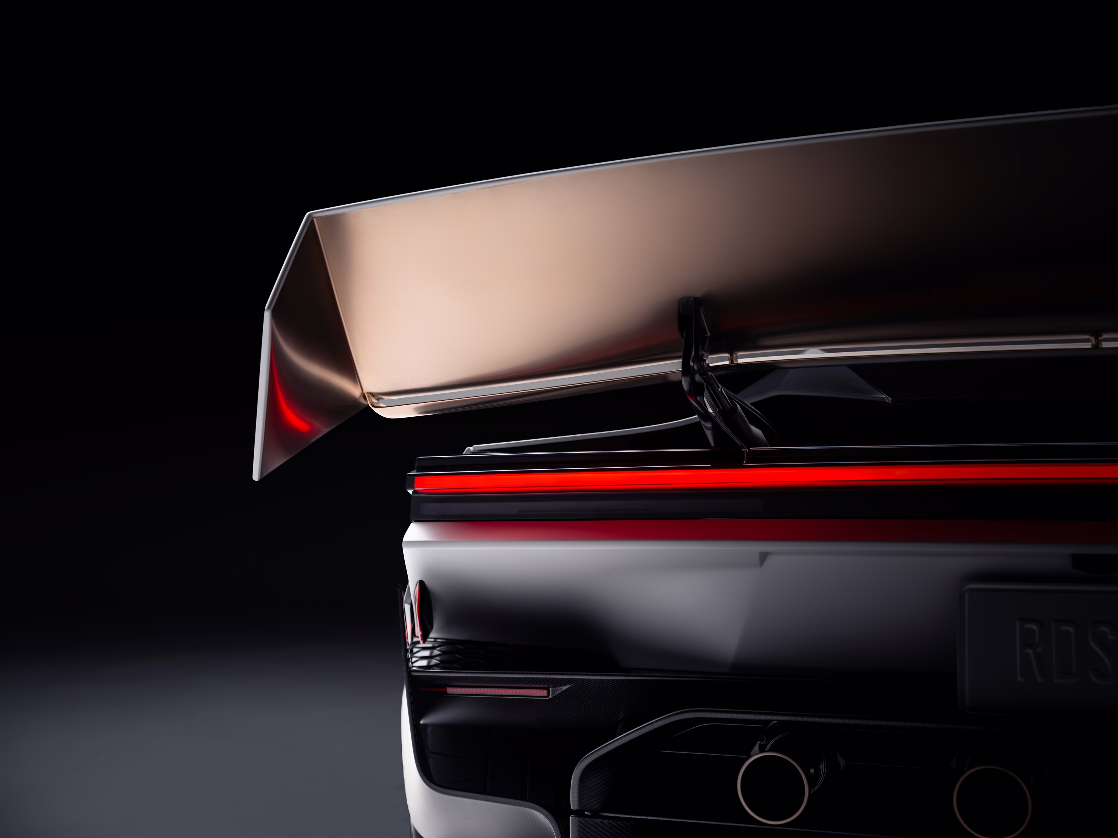 Asa traseira elevada sobre a faixa luminosa vermelha do Roadster