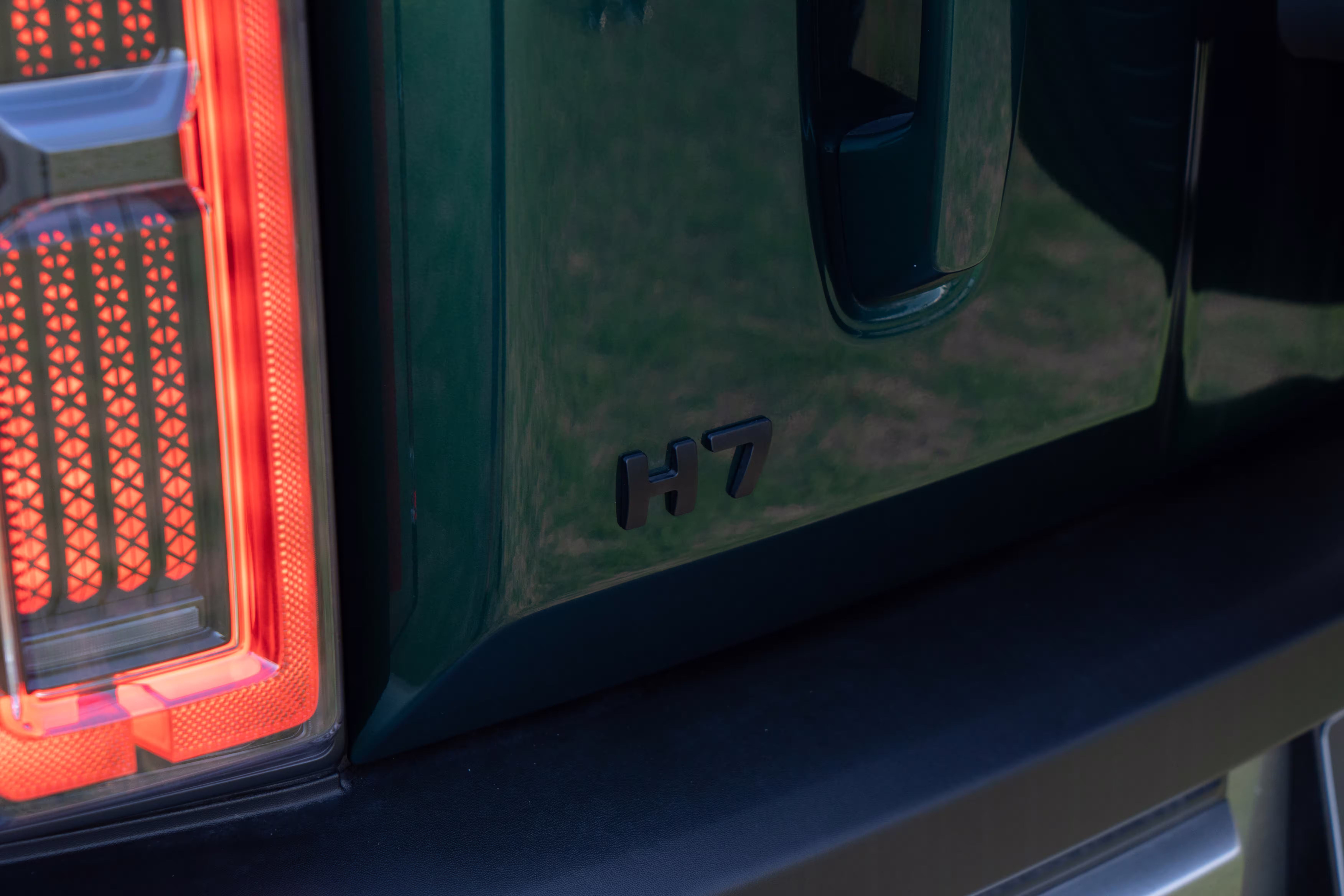 Foto de divulgação: Emblema H7 e parte da lanterna traseira do SUV verde.