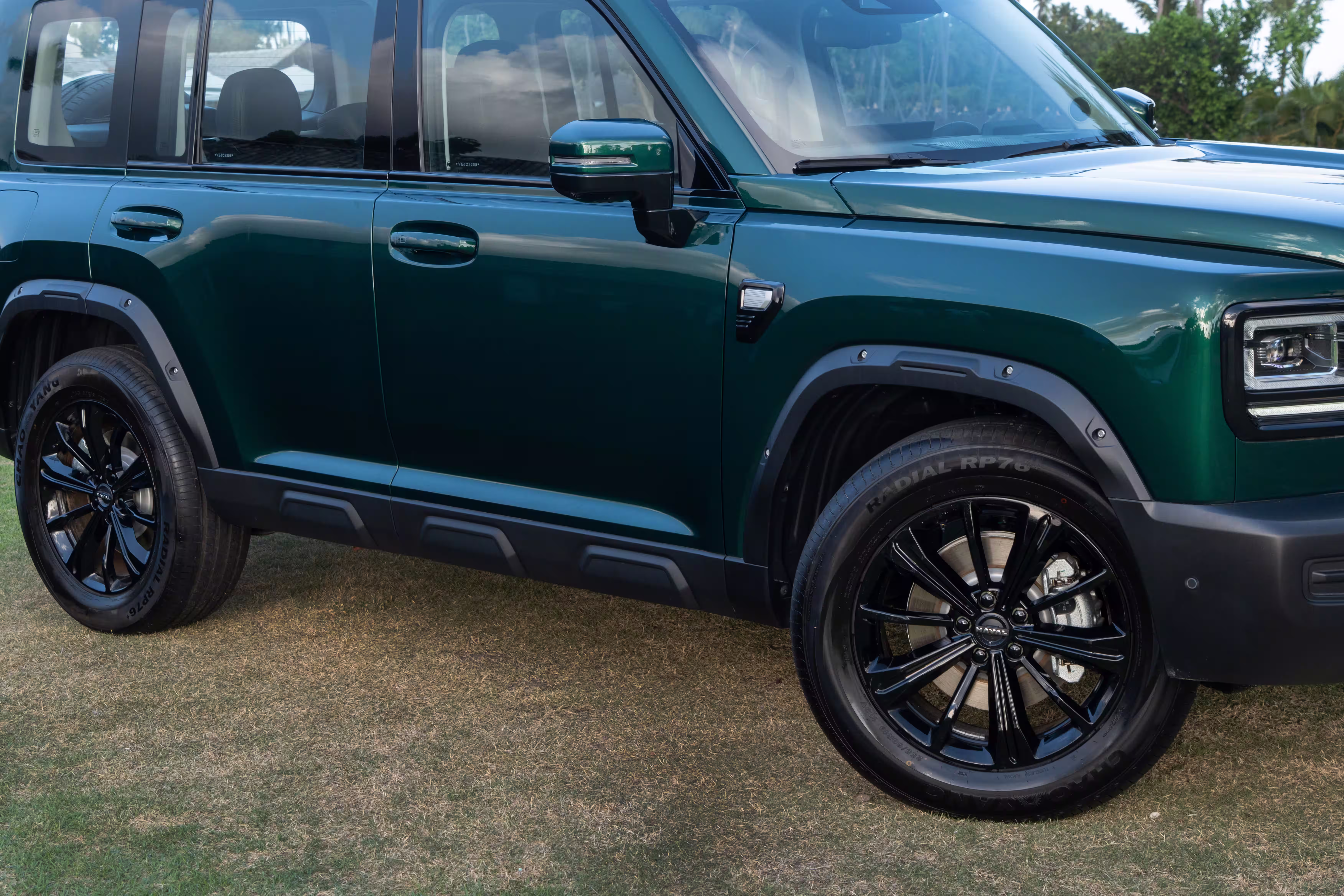Foto de divulgação: Lateral dianteira do Haval H7 verde com portas, molduras pretas e roda dianteira.