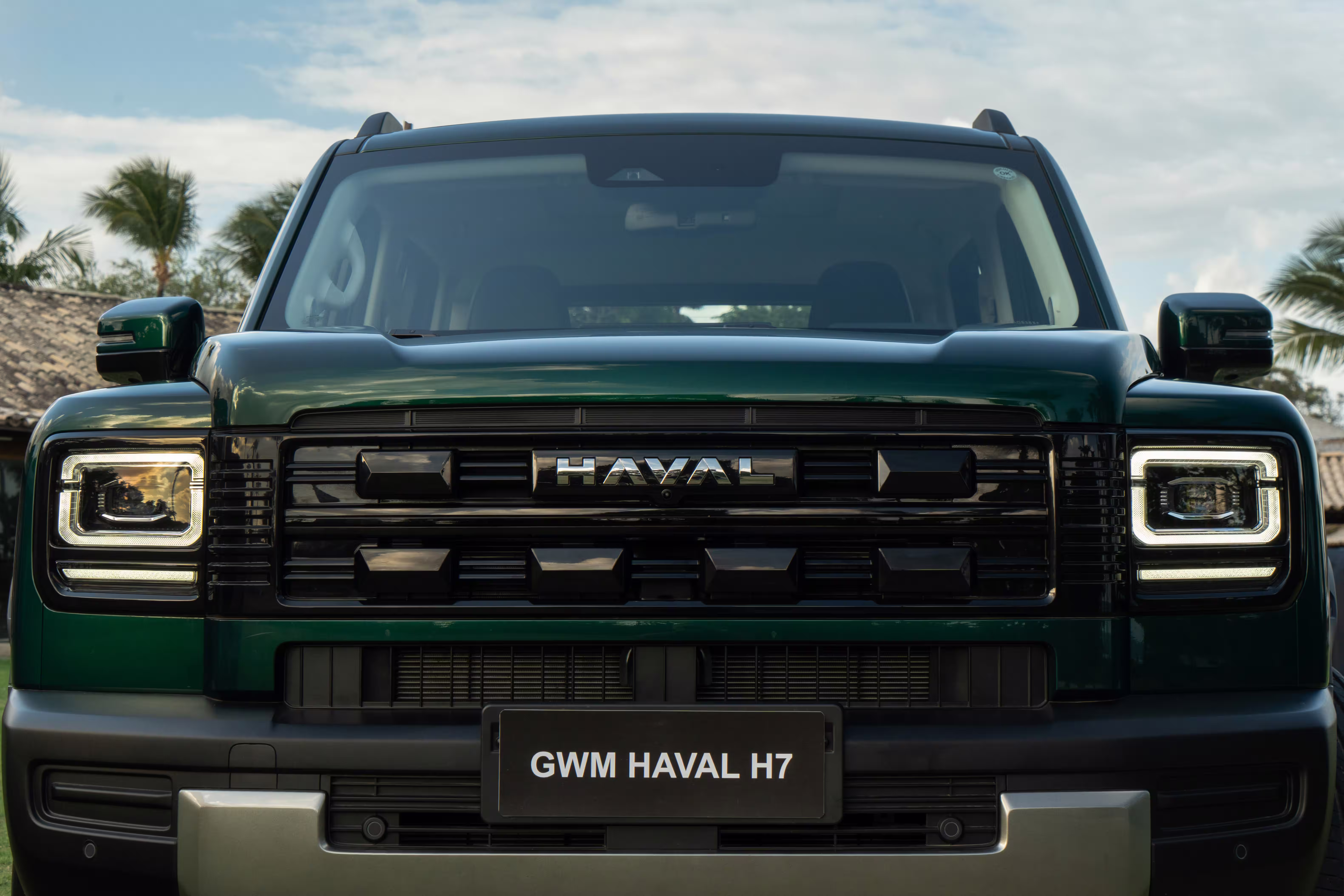 Foto de divulgação: Dianteira do Haval H7 verde com faróis acesos, grade e para-choque em primeiro plano.
