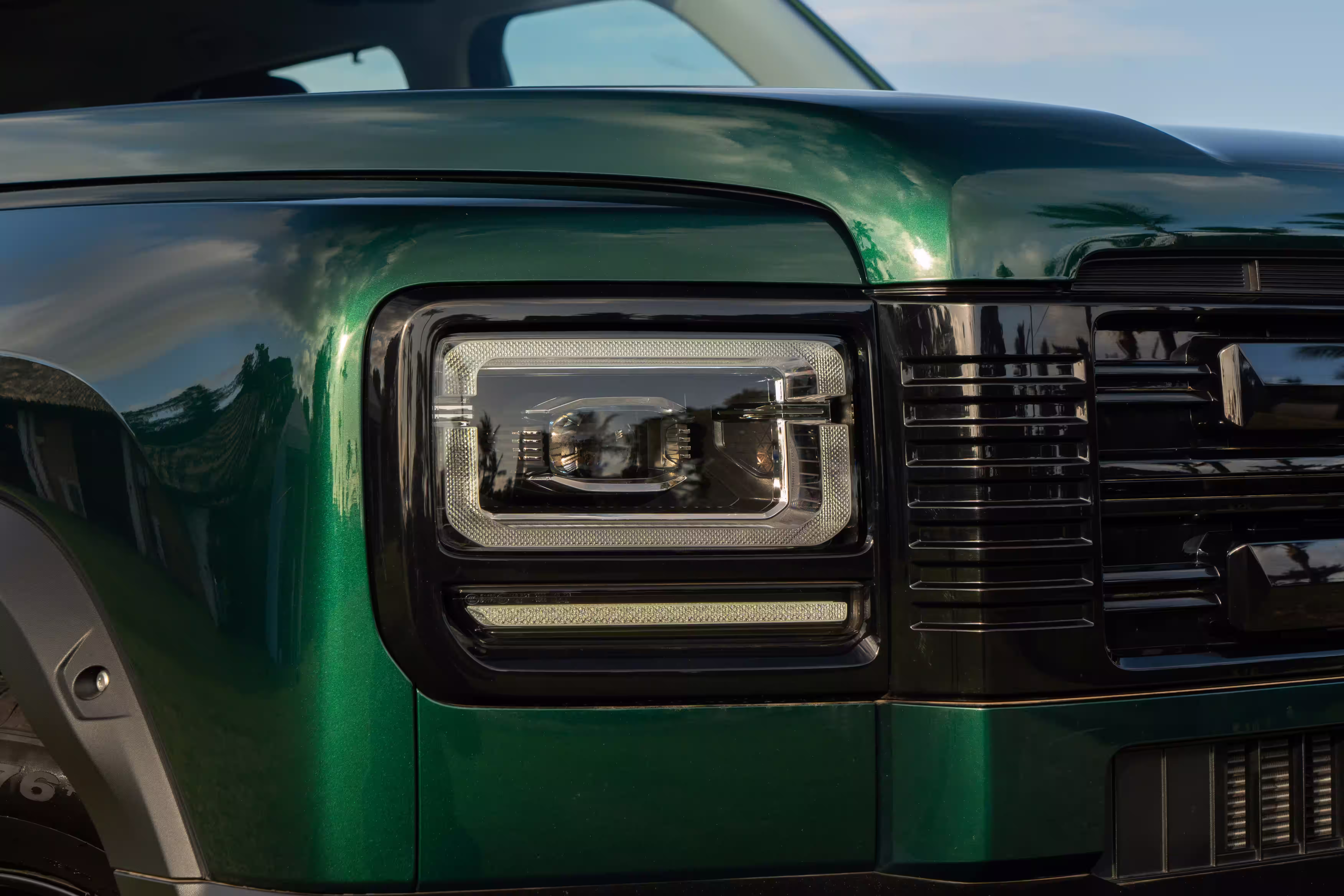 Foto de divulgação: Detalhe do farol retangular e da borda da grade do Haval H7 verde.