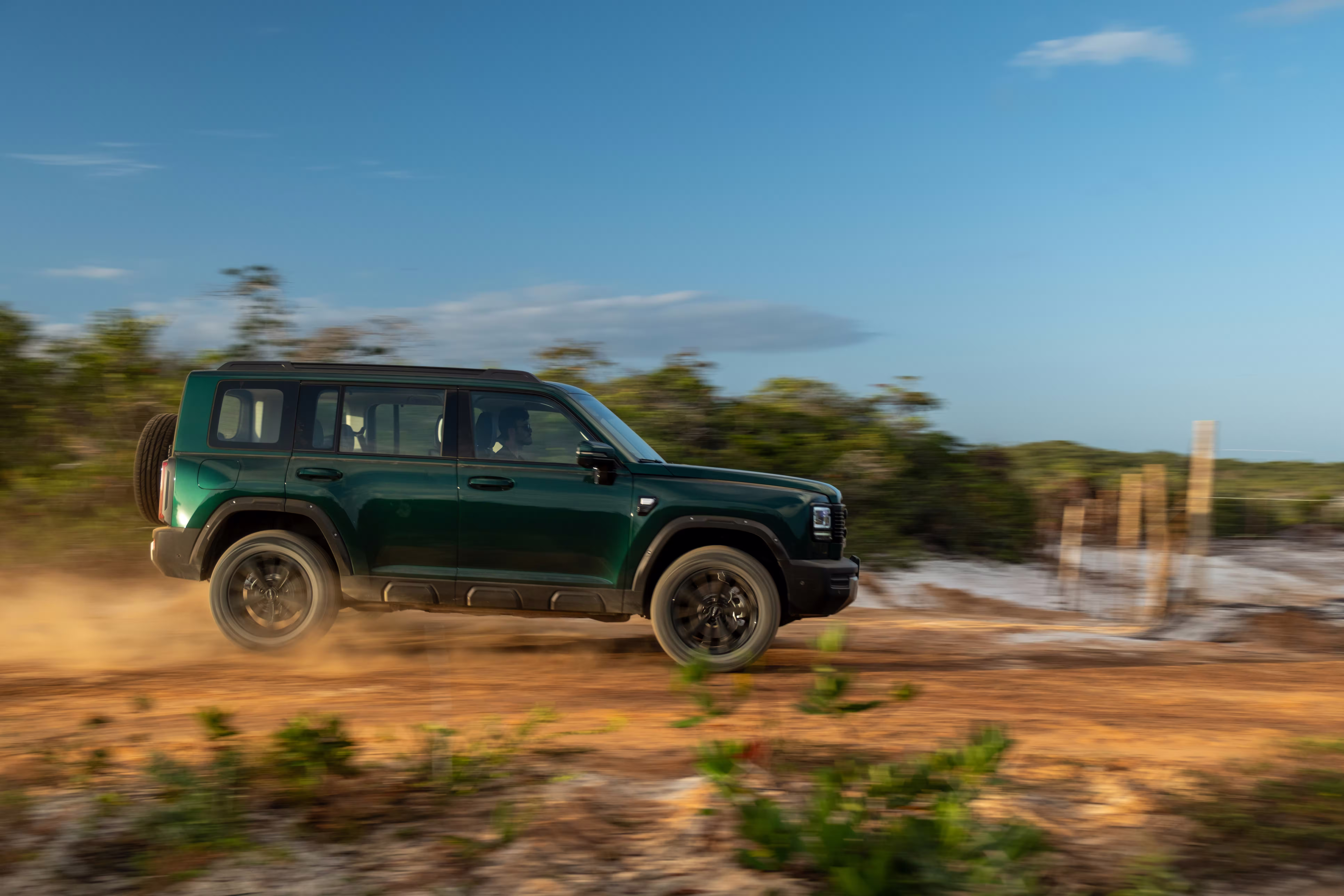 Foto de divulgação: Haval H7 verde de perfil em movimento sobre terra, com poeira junto às rodas.