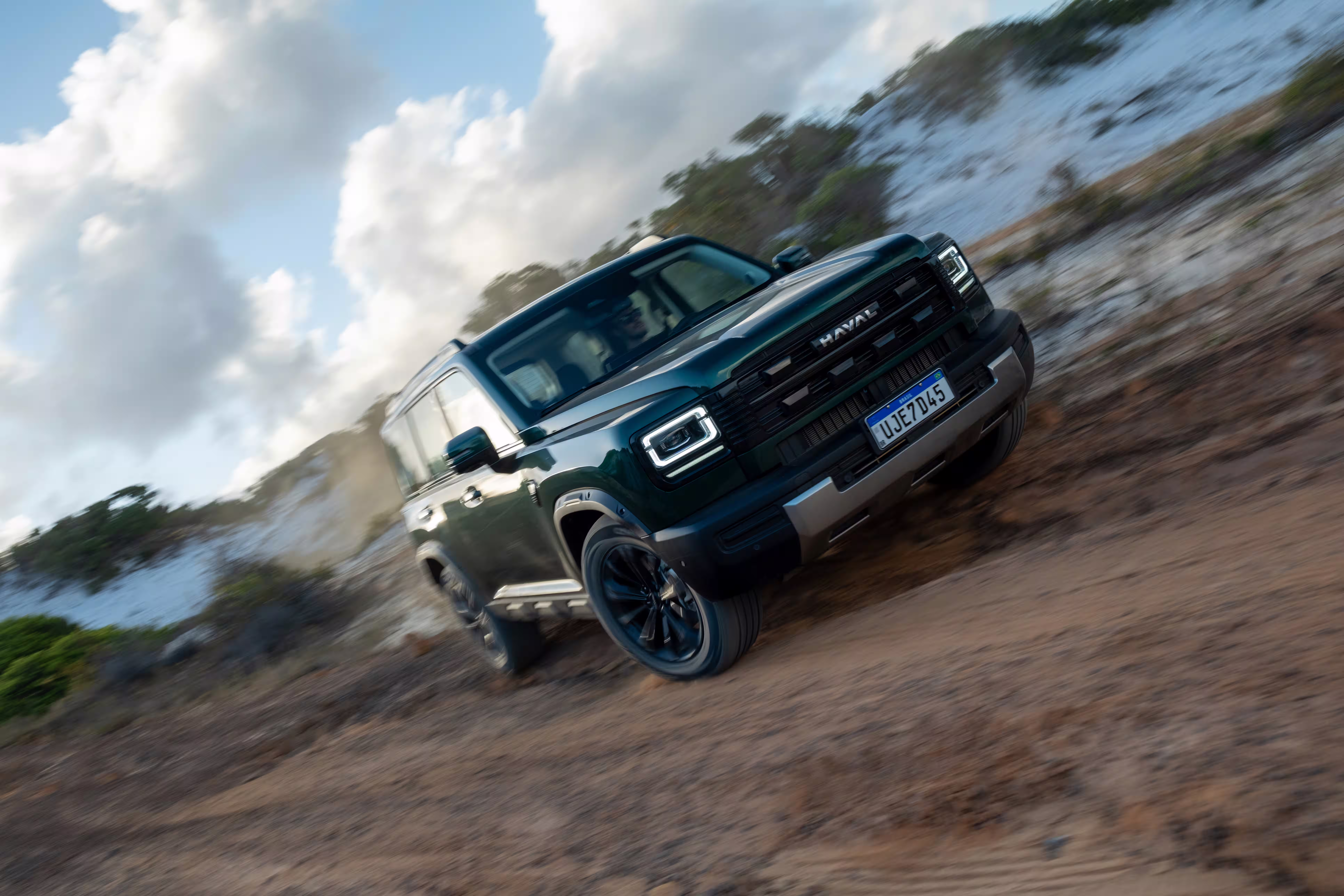 Foto de divulgação: Haval H7 verde em três quartos dianteiros numa passagem de terra fotografada em ângulo inclinado.