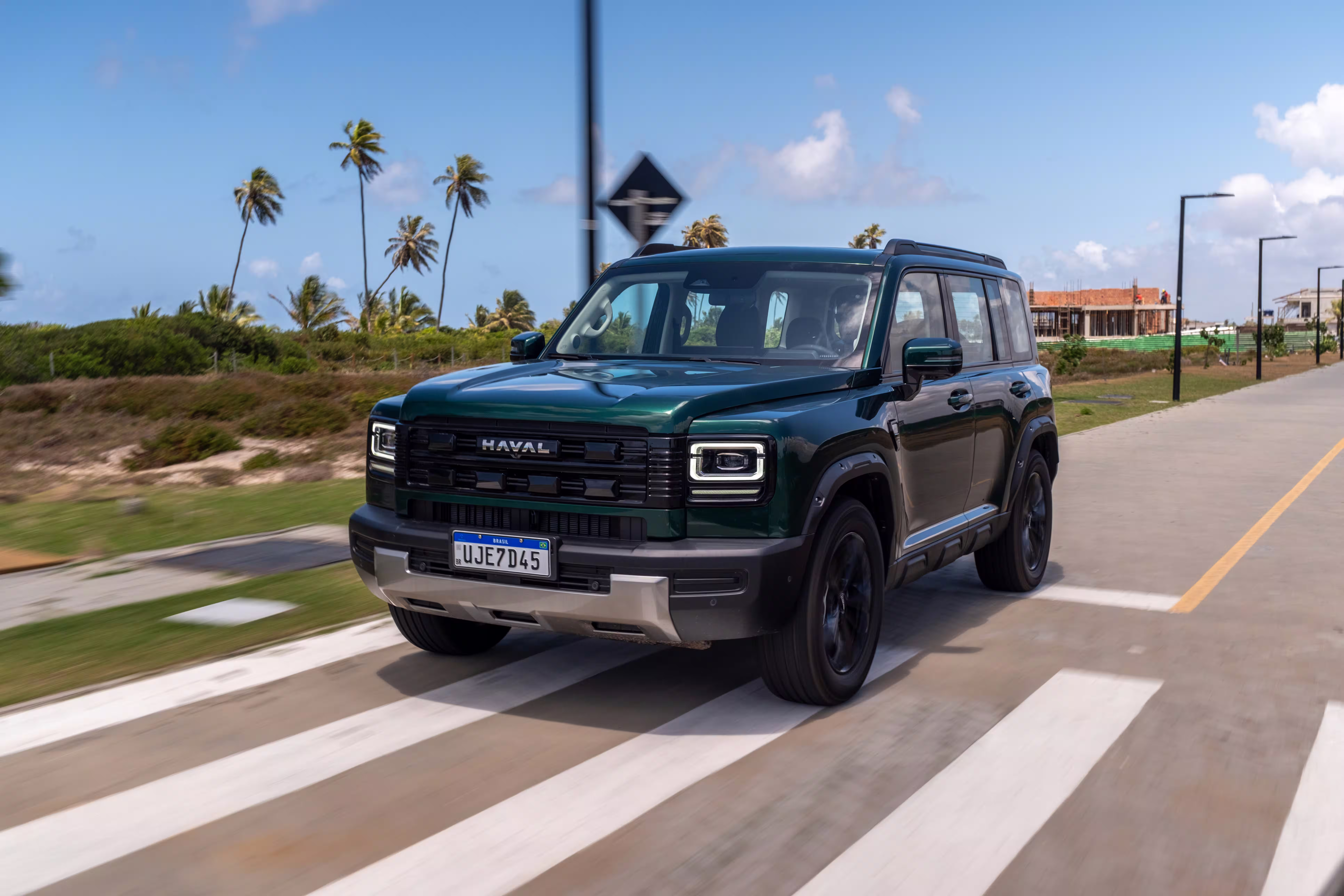 Foto de divulgação: Haval H7 verde em três quartos dianteiros, atravessando uma faixa de pedestres no asfalto.