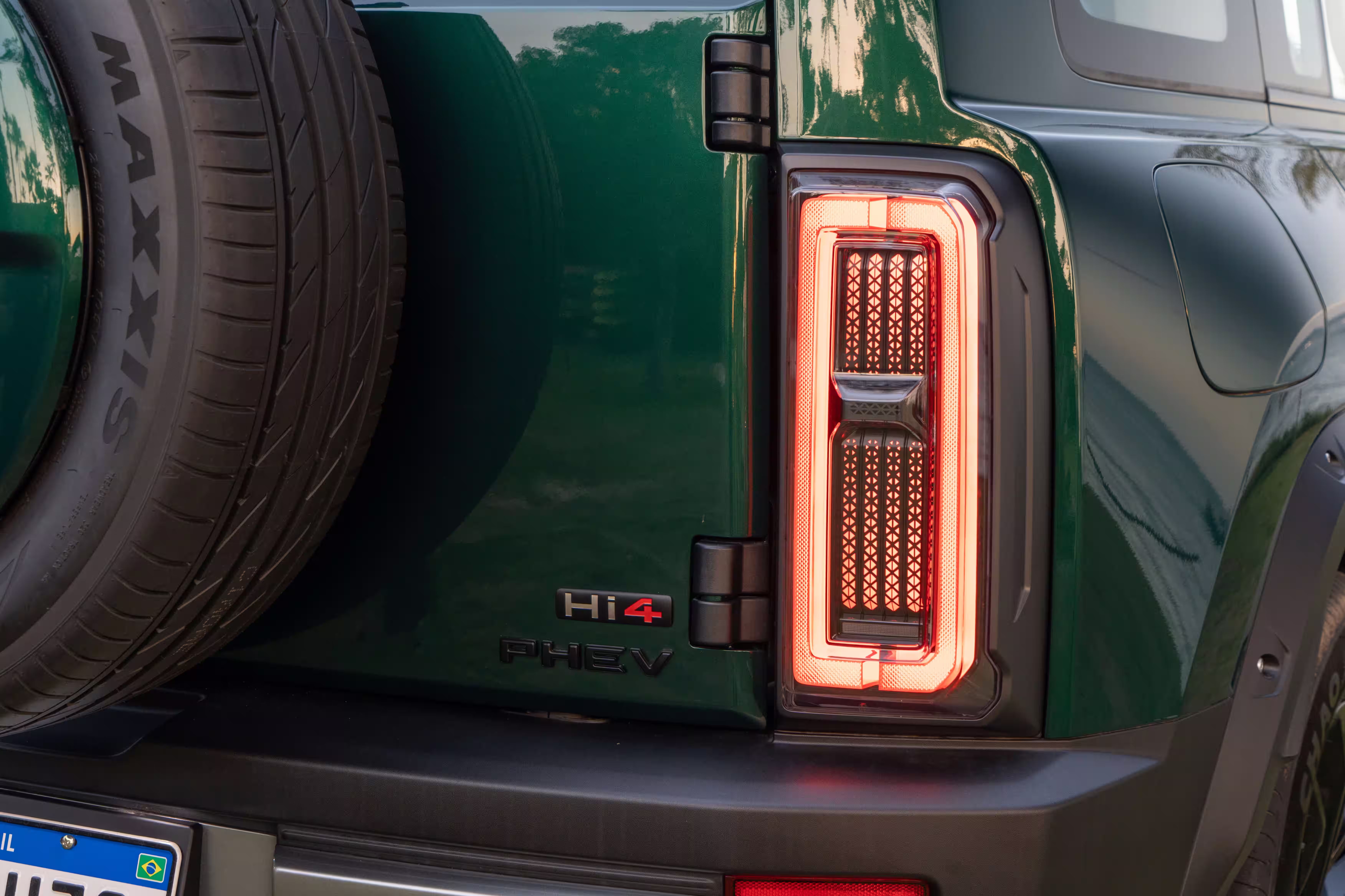 Foto de divulgação: Detalhe da lanterna traseira do Haval H7 junto ao estepe e aos emblemas Hi4 e PHEV.