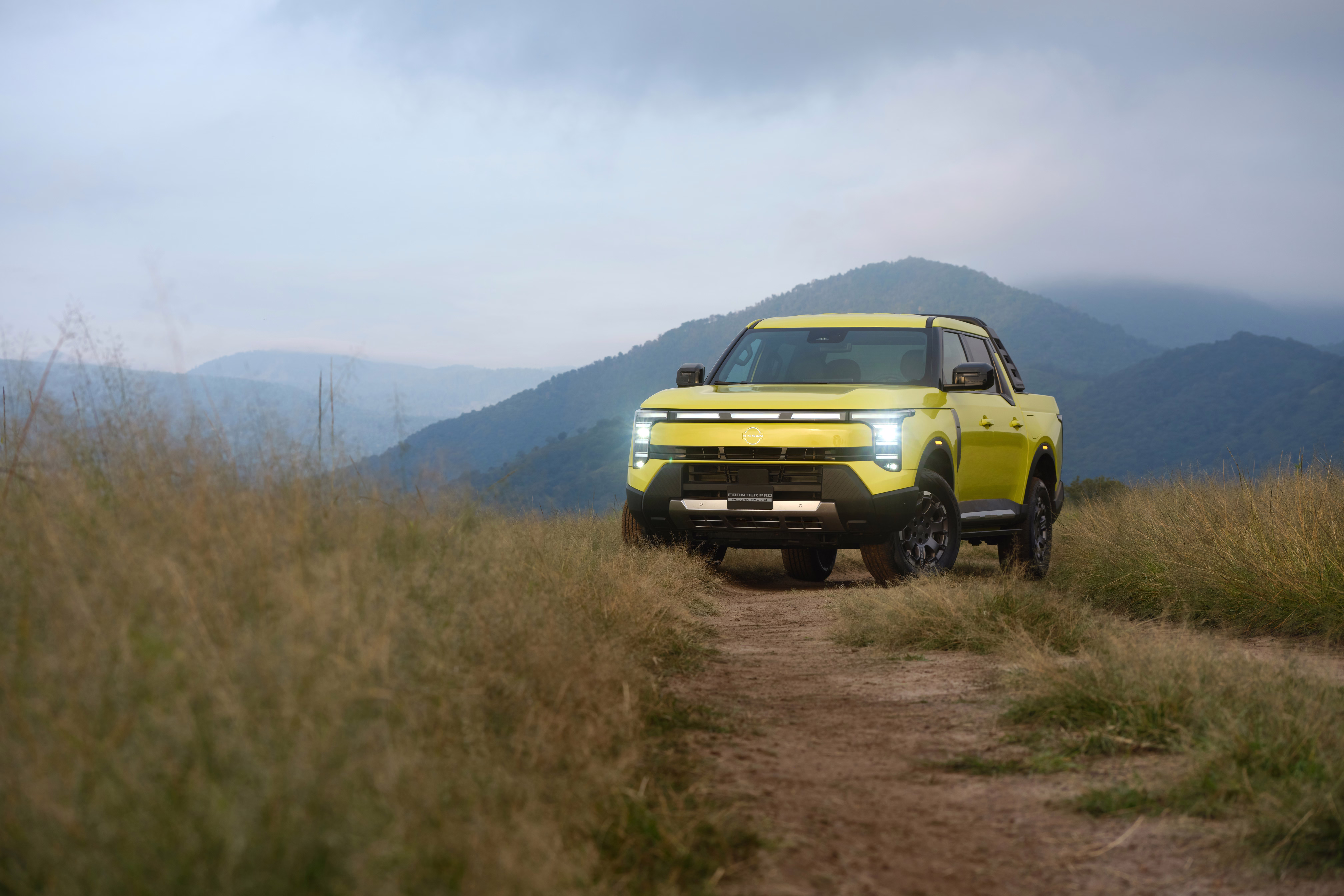 Nissan Frontier Pro vista à distância em uma estrada estreita de terra