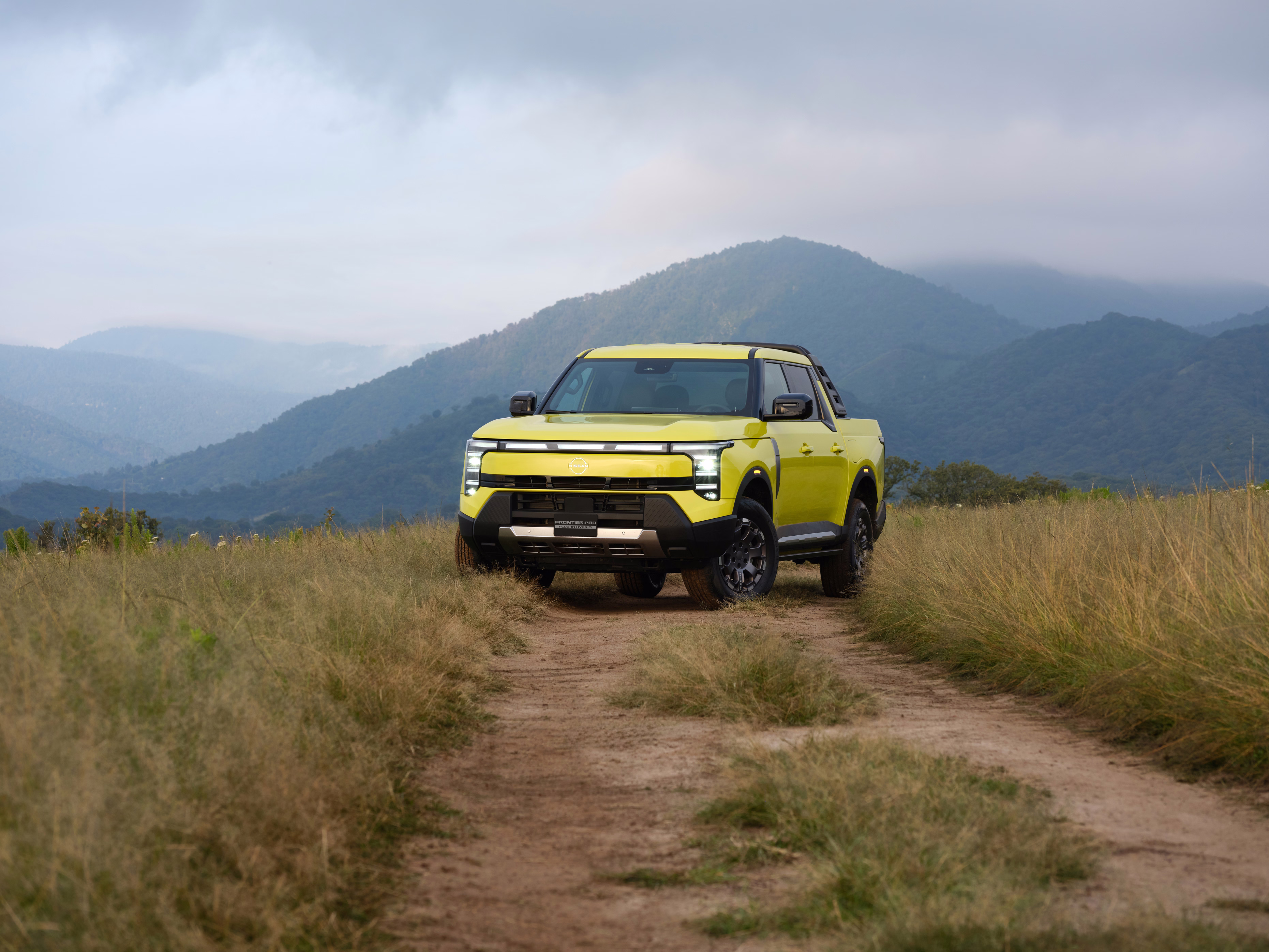 Frontier Pro amarela em enquadramento amplo diante de uma paisagem verde
