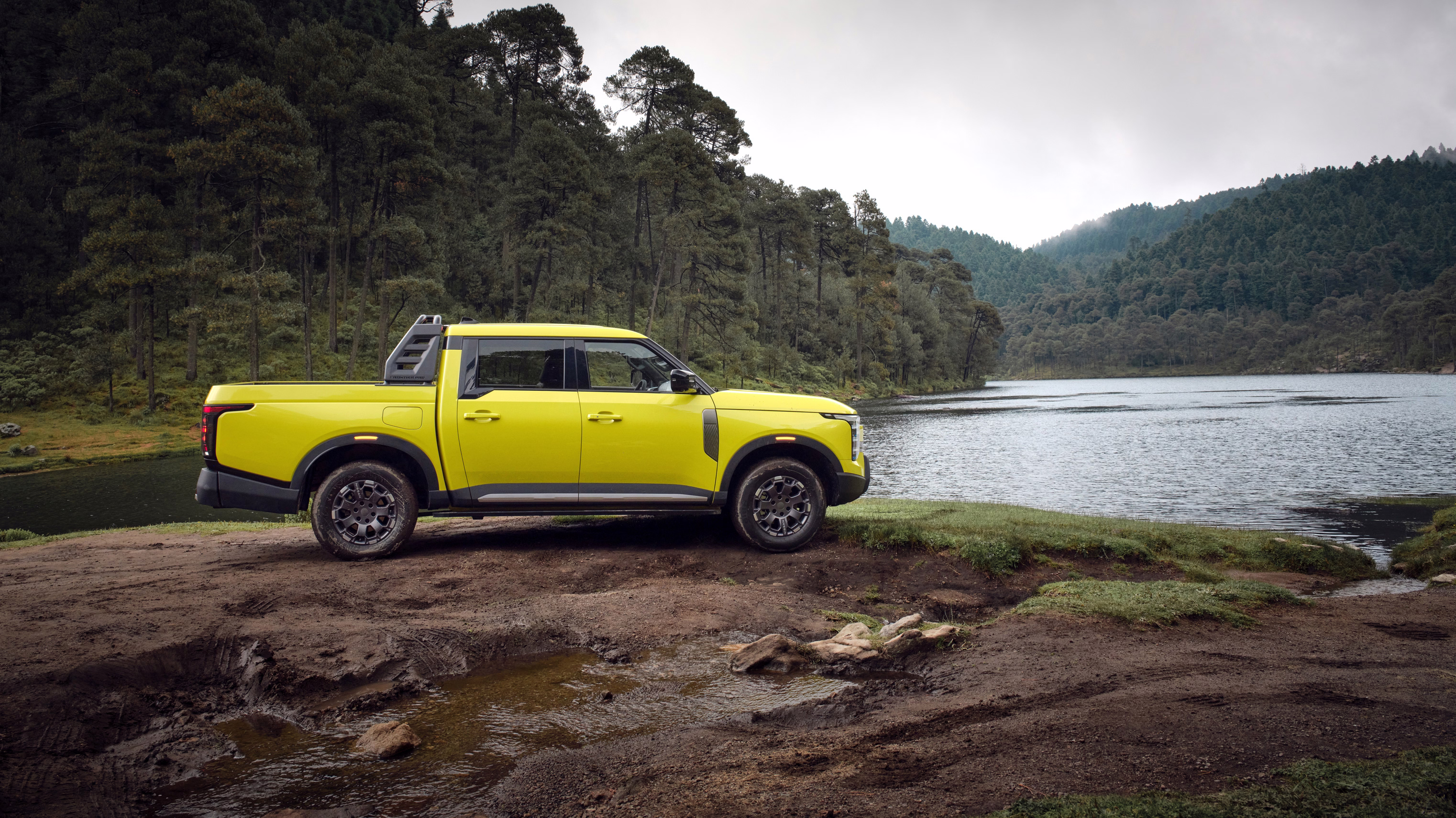Perfil completo da Nissan Frontier Pro amarela à beira de um lago