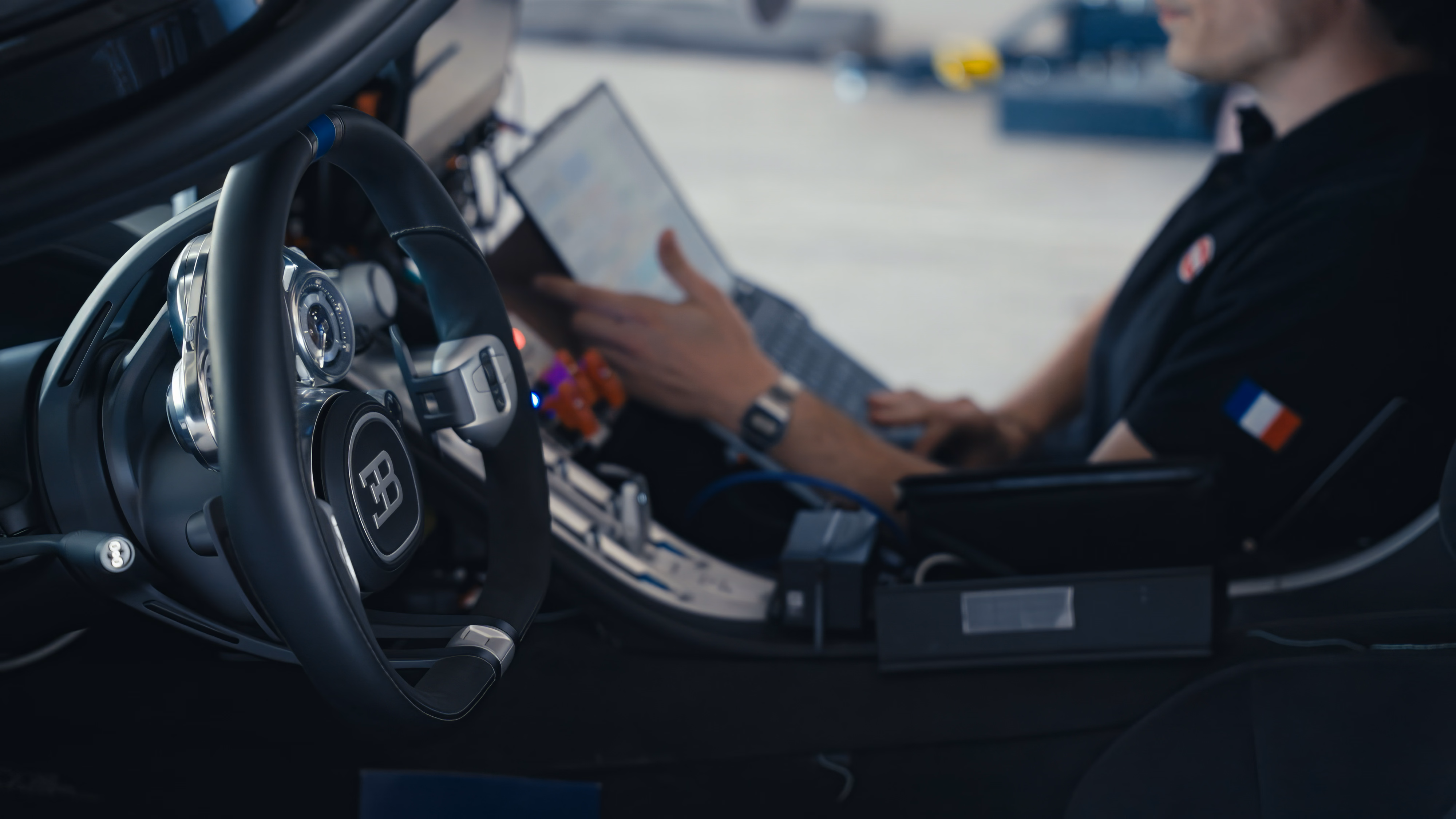 Cockpit do Bugatti Tourbillon com volante, equipamentos de teste e técnico usando computador