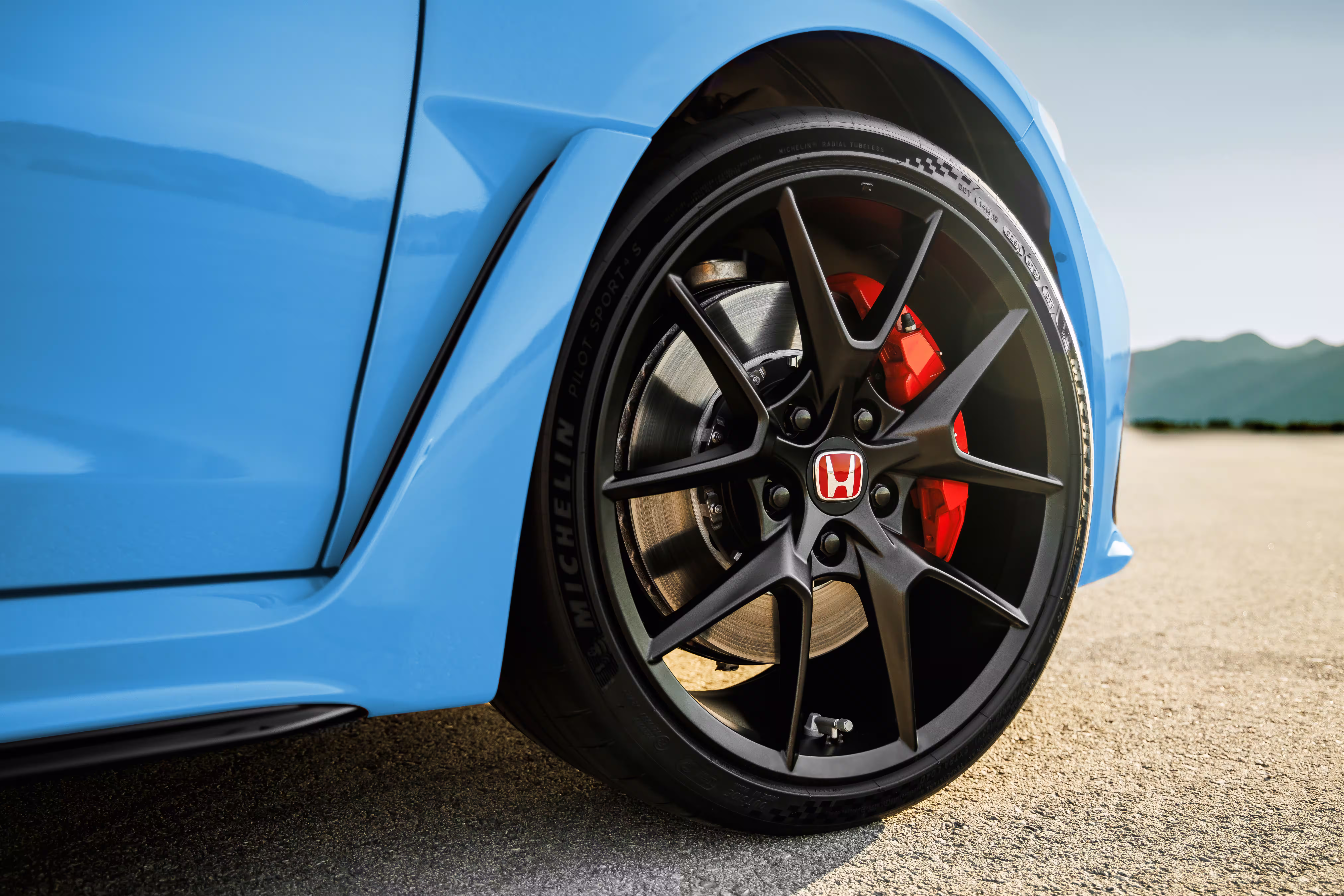Detalhe da roda dianteira preta e pinça de freio vermelha do Honda Civic Type R 2027 azul