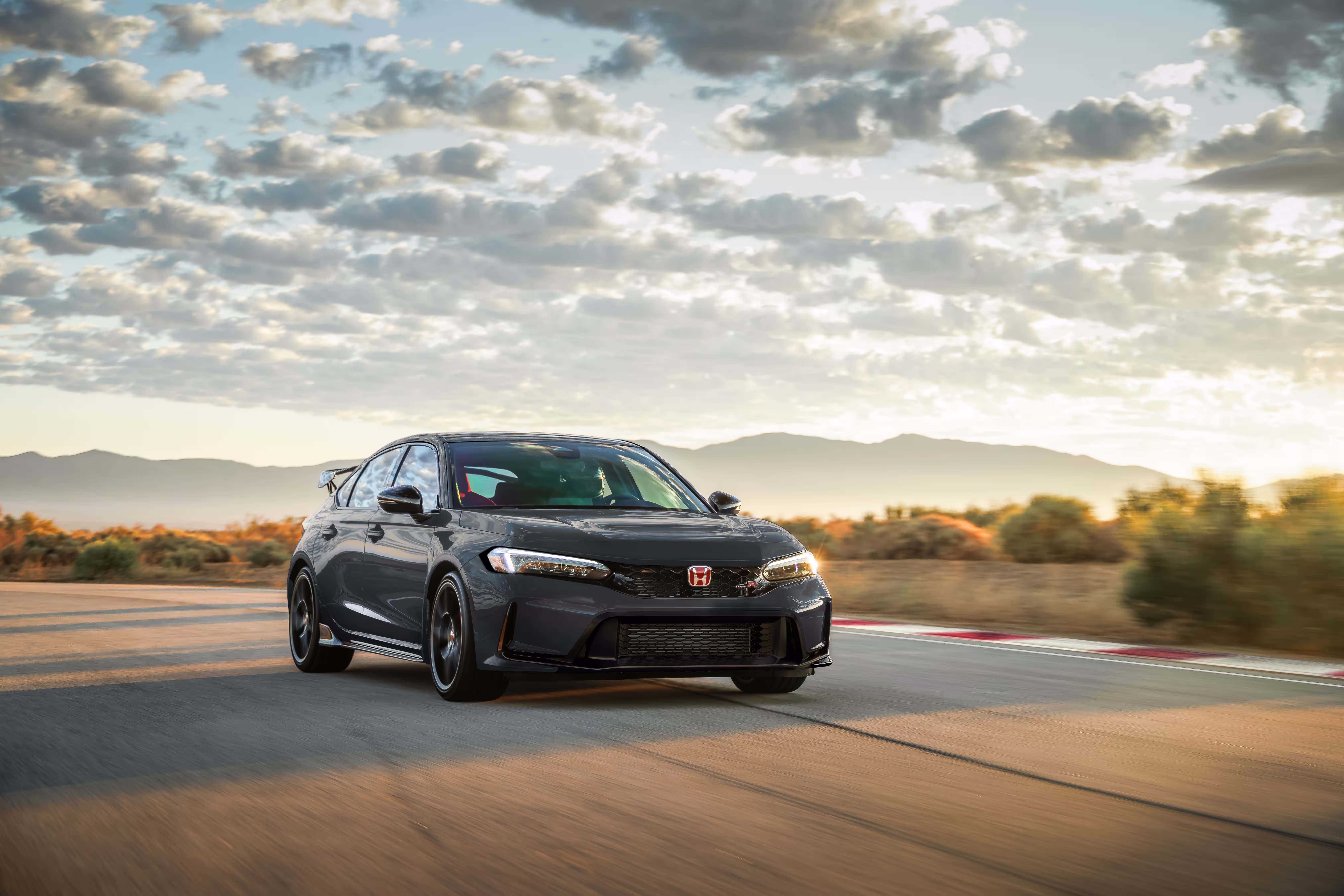 Honda Civic Type R 2027 cinza em três quartos dianteiros, em movimento ao entardecer
