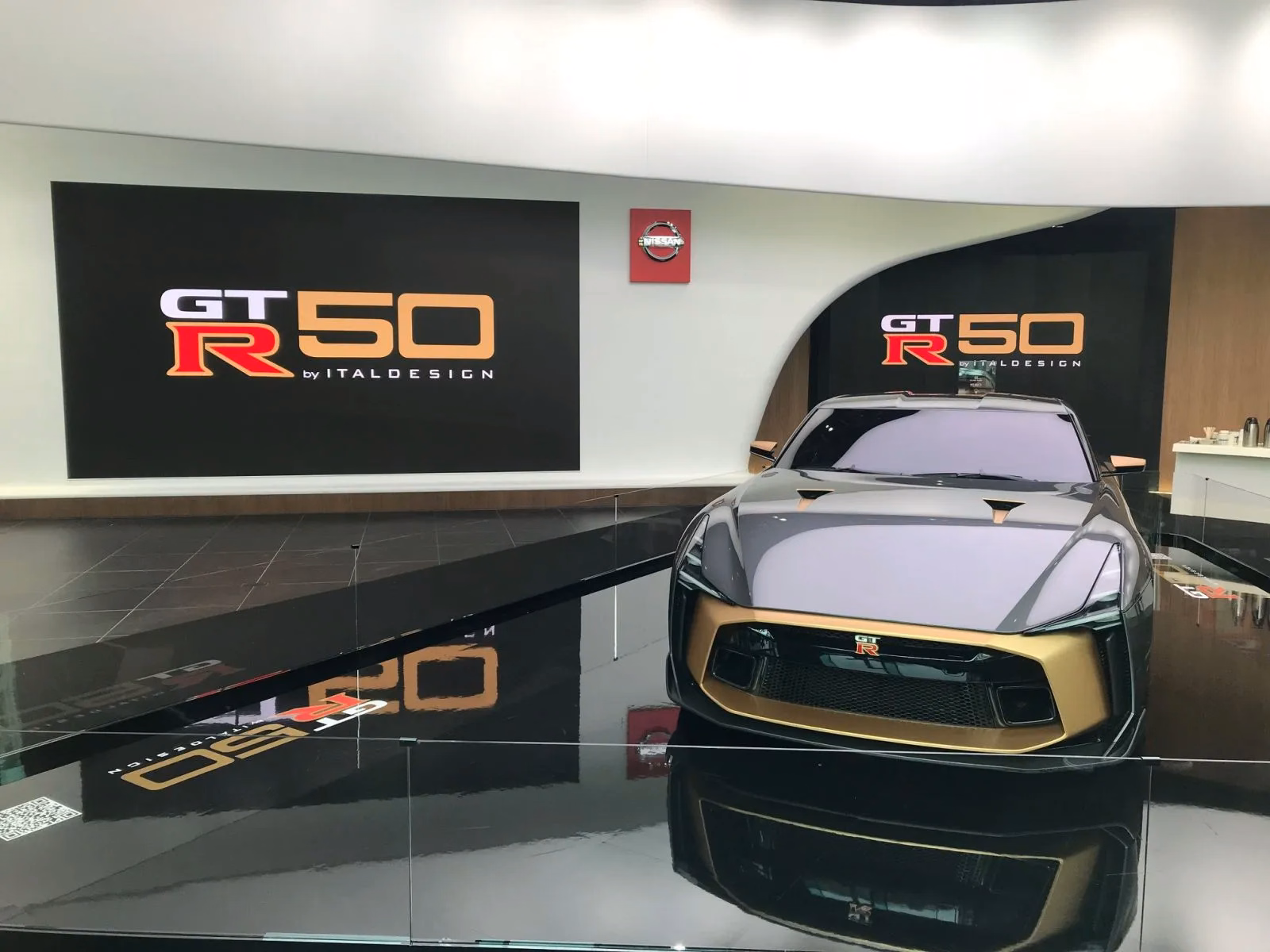 GT-R50 cinza e dourado exposto diante de painéis Nissan Crossing