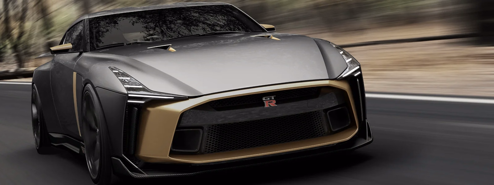 Enquadramento panorâmico do GT-R50 cinza e dourado em movimento pela dianteira