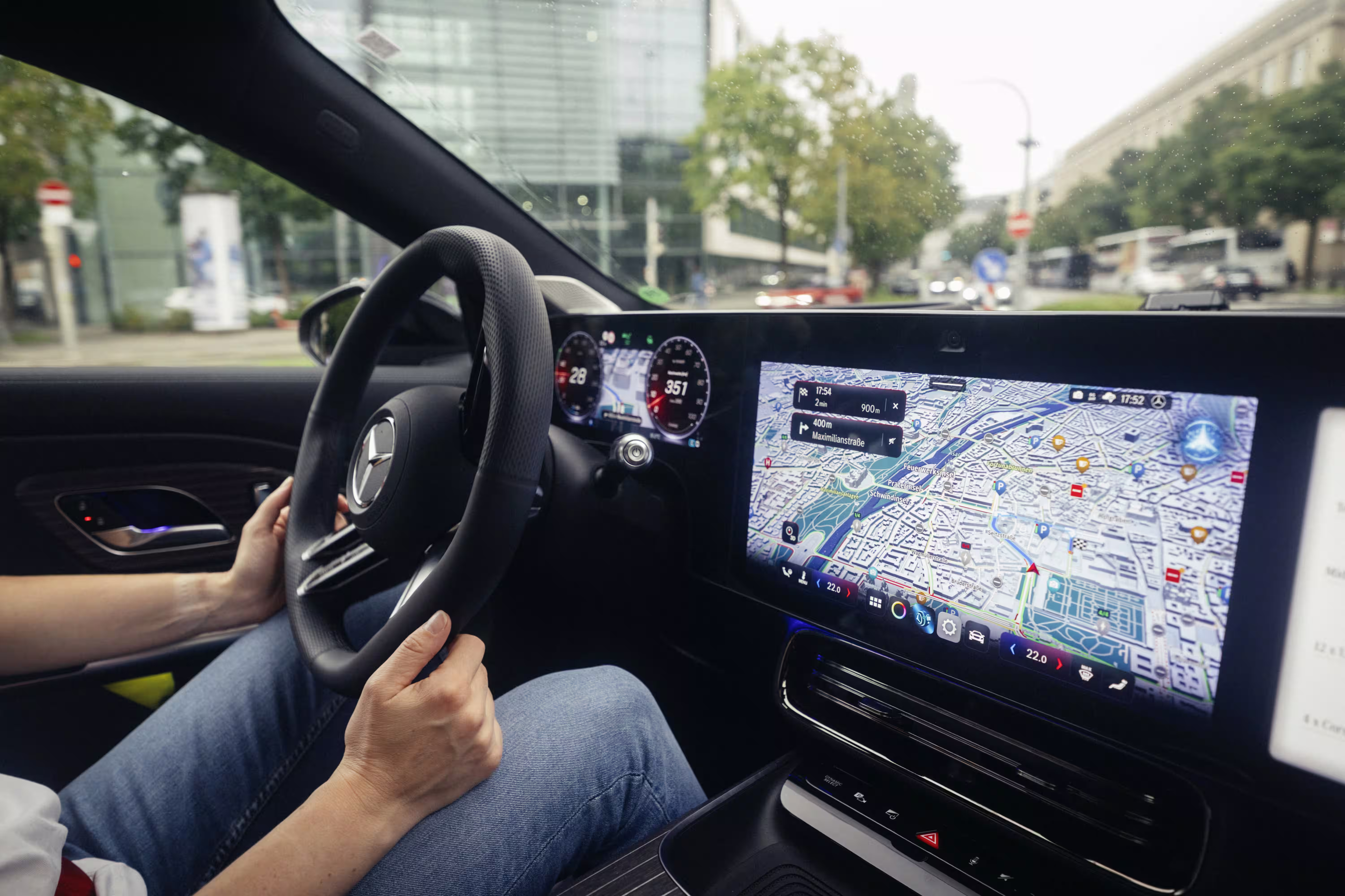 Motorista segurando o volante de um Mercedes-Benz com mapa de navegação na tela central do painel