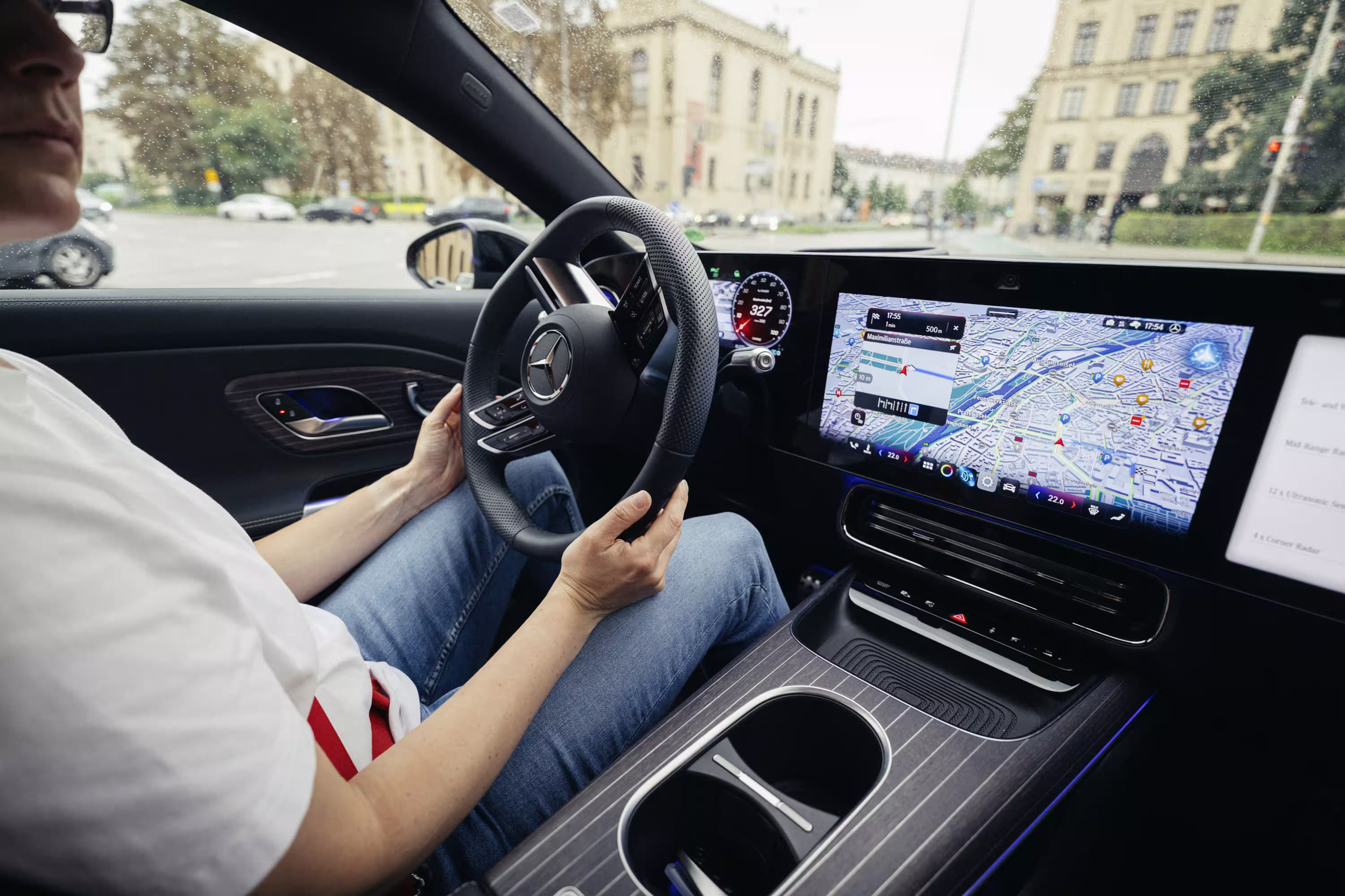 Vista ampla da cabine de um Mercedes-Benz de demonstração com motorista ao volante, console e mapa na tela
