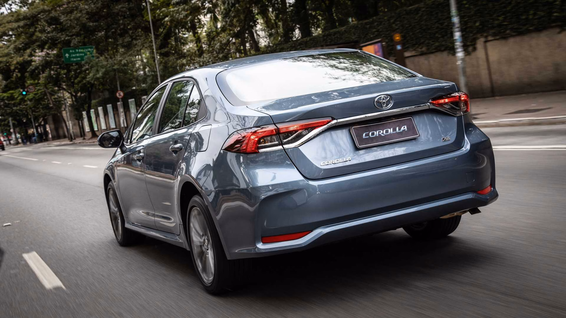 Toyota Corolla 2020 cinza visto em três quartos traseiros em movimento na cidade